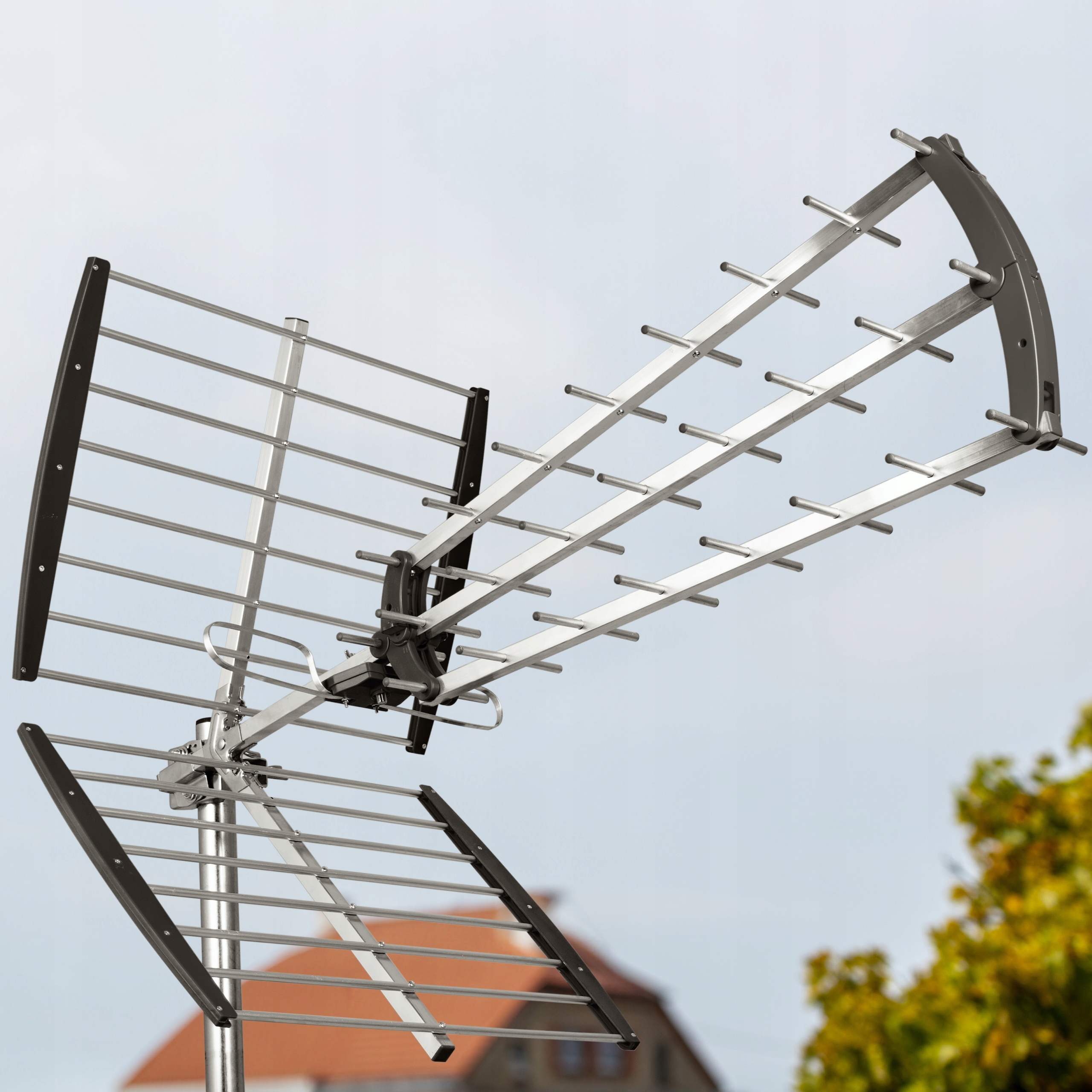 Metalowa antena telewizyjna z czarnymi akcentami na tle dachu domu.