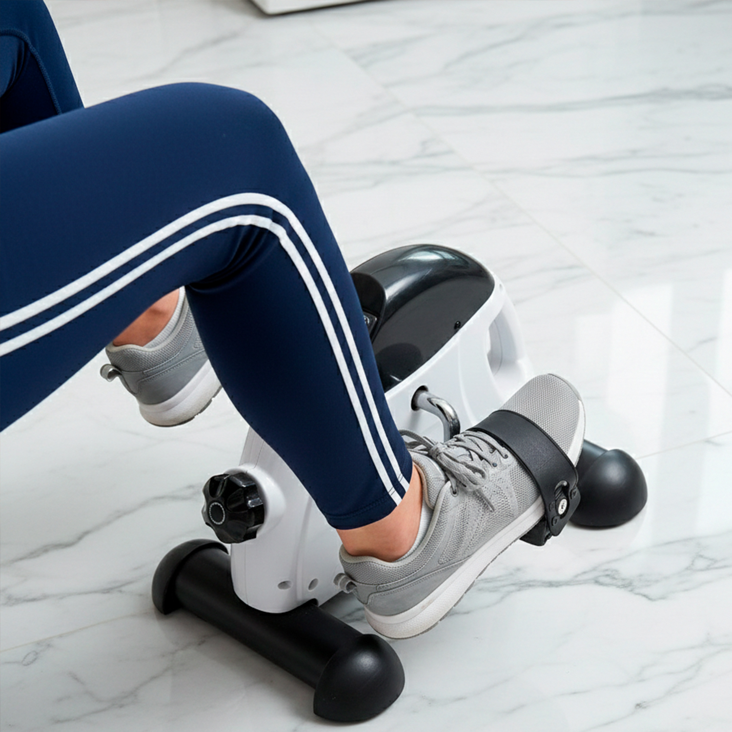 Persona haciendo ejercicio en bicicleta estática. Pantalón azul, zapatos grises.