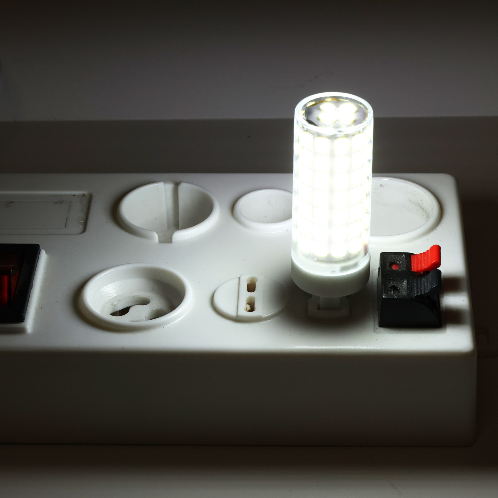 Una bombilla LED brillante en una regleta blanca con interruptores.