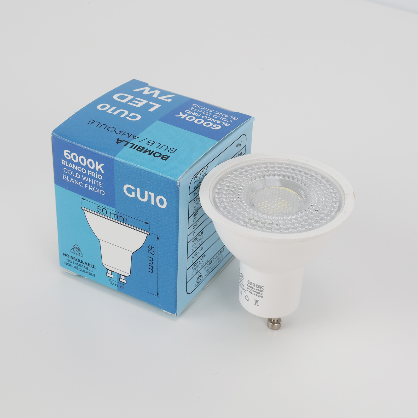 Una bombilla LED GU10 blanca está junto a su empaque azul.