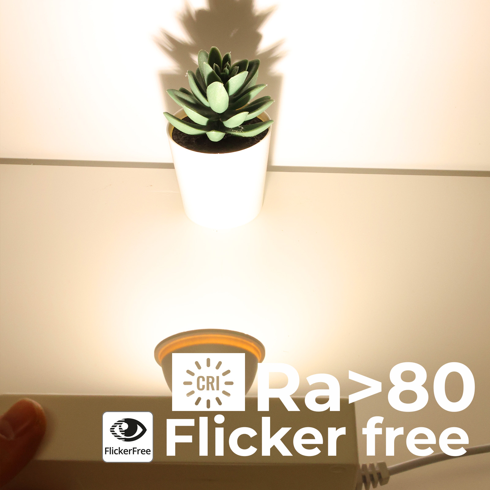 Planta artificial en maceta sobre lámpara con texto 'Ra<gt/>80 Flicker free'.