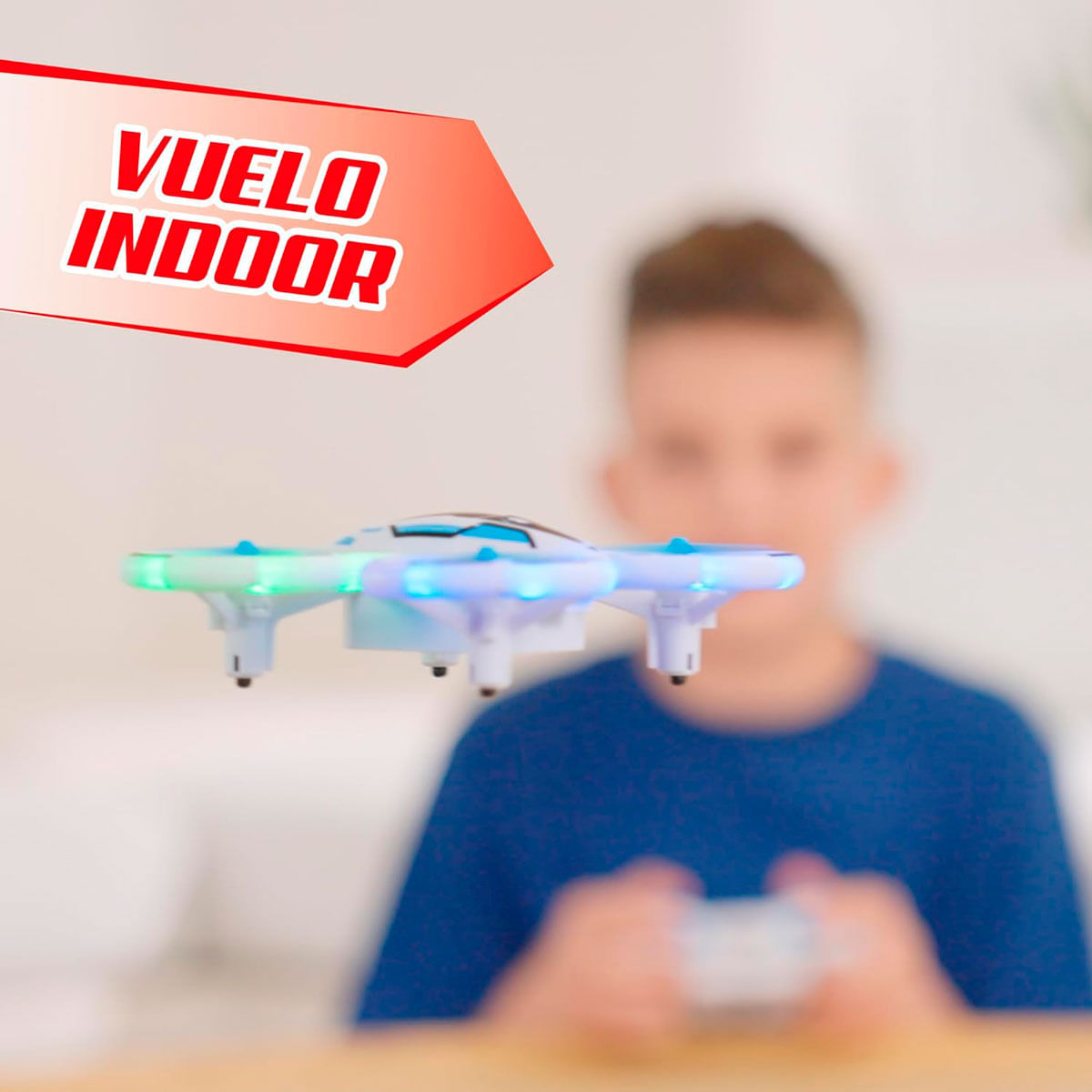 Un ragazzo gioca con un drone. Il drone è illuminato da luci blu e verdi. Testo "VUELO INDOOR".