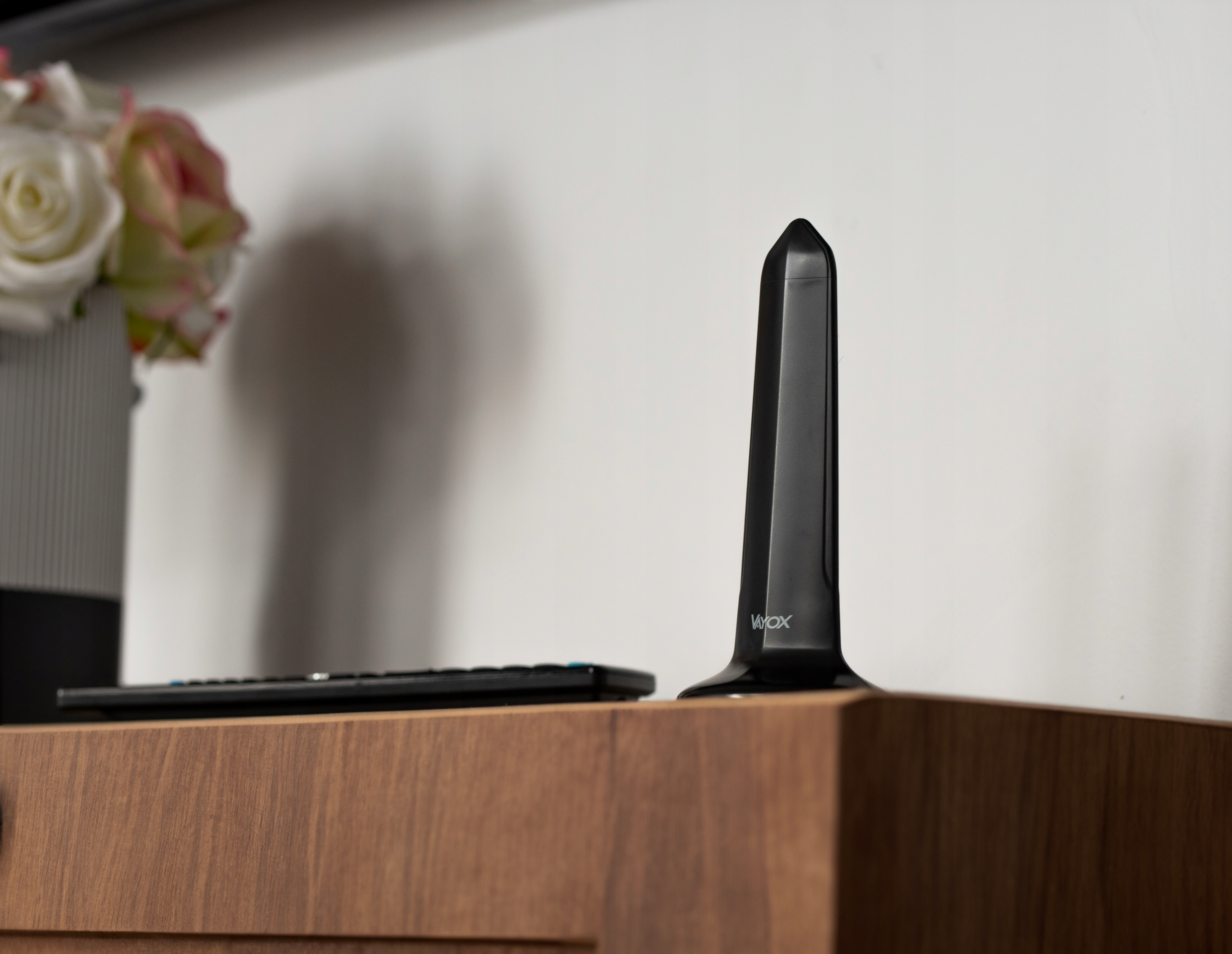 Czarna antena Voxx obok pilota na drewnianej powierzchni.