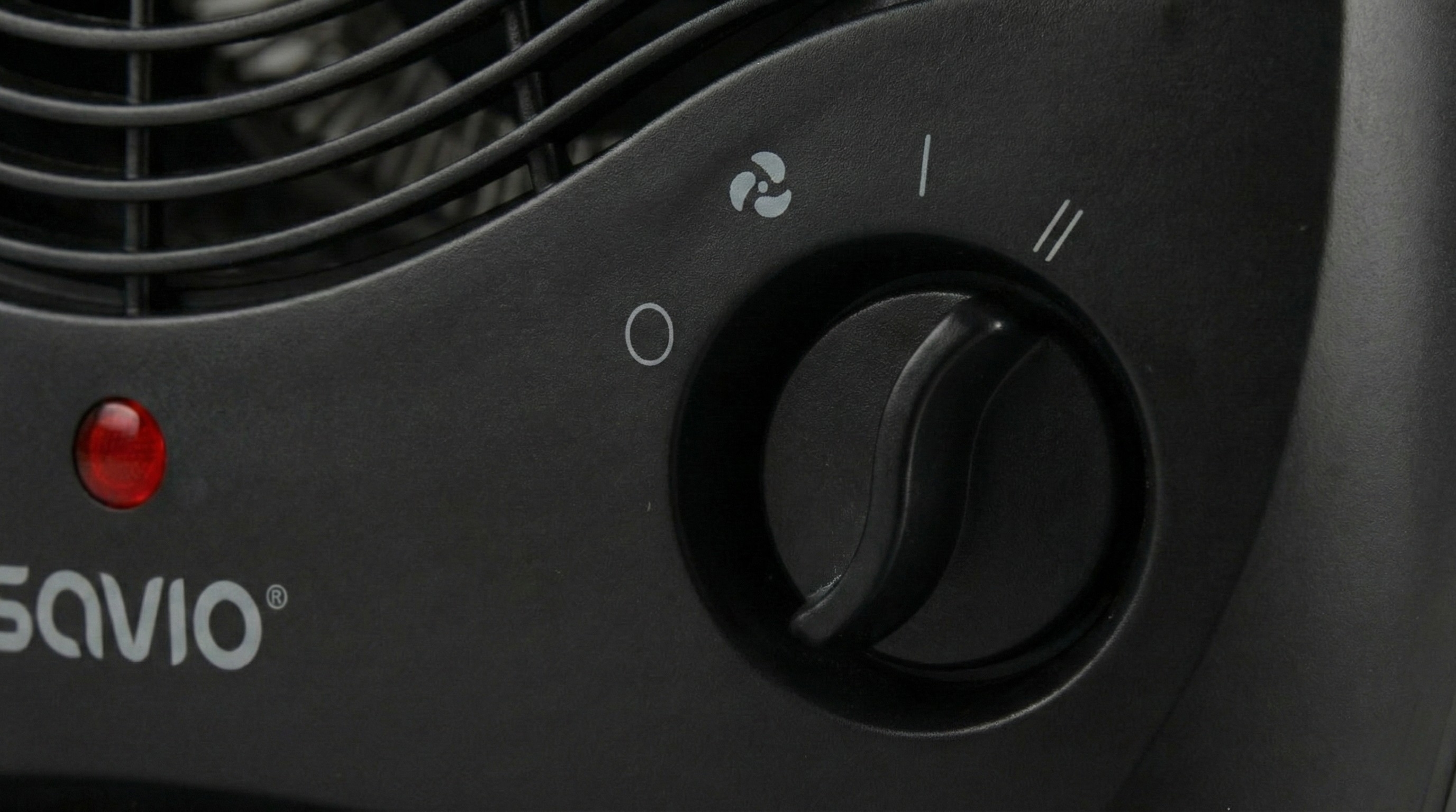 Zbliżenie czarnego grzejnika z czerwoną lampką kontrolną i pokrętłem obrotowym.