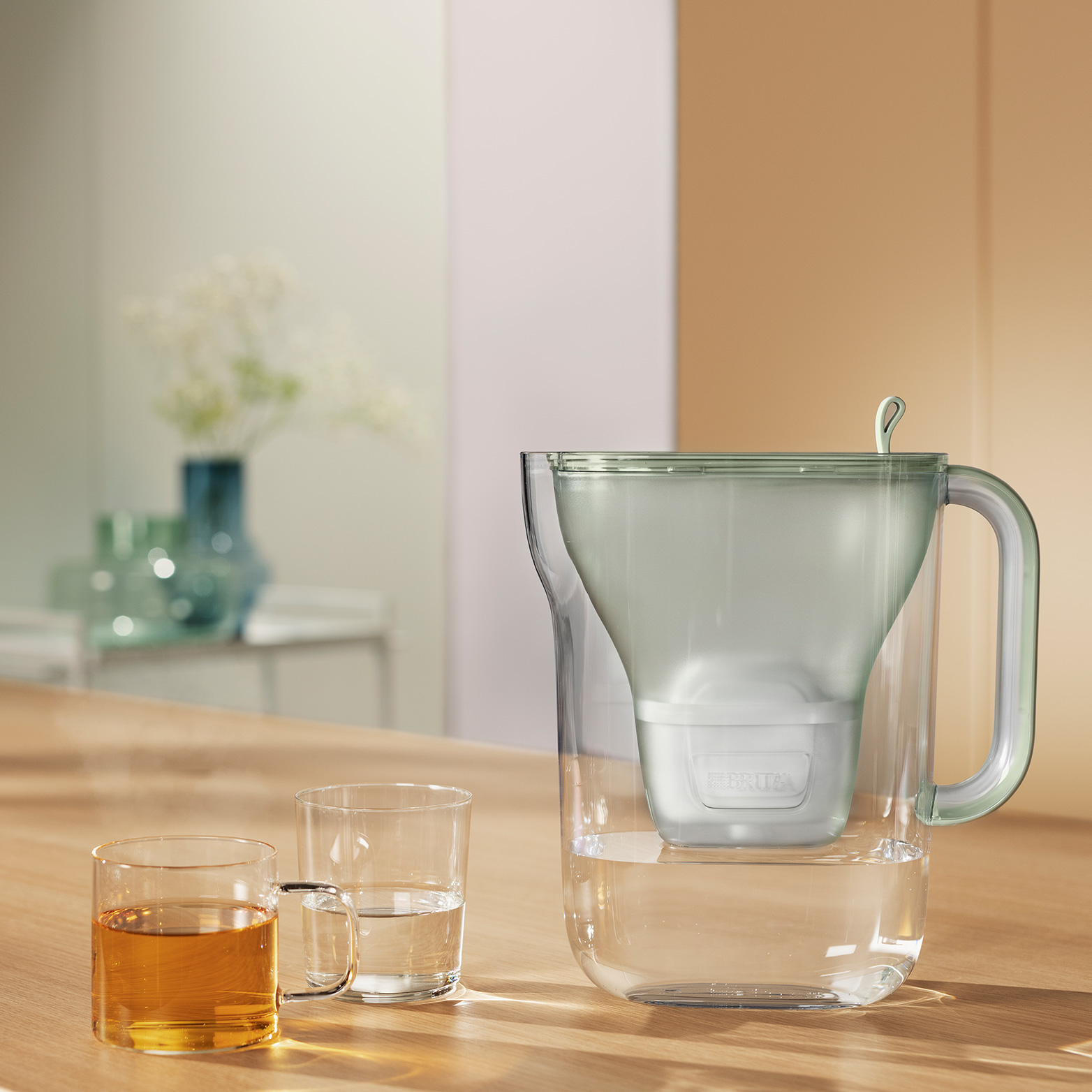 Ein Brita-Wasserfilterkrug mit zwei Gläsern auf einem Holztisch.