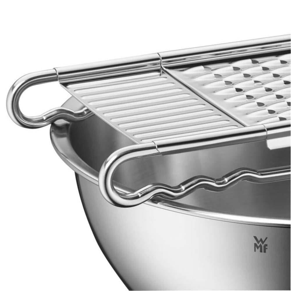 Un accessorio grattugia in metallo argentato su una ciotola in acciaio inox.