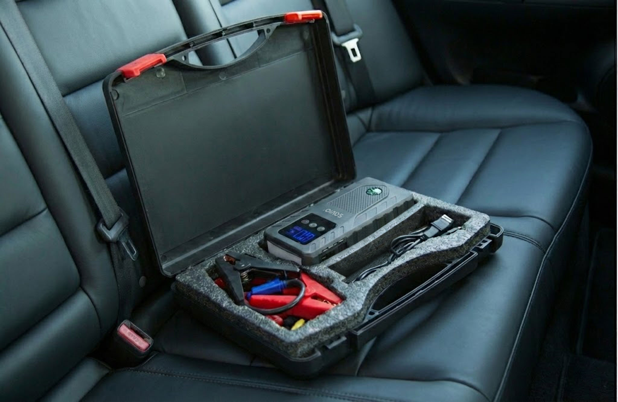Zestaw do rozruchu awaryjnego z klemami i kablami w walizce na skórzanym tylnym siedzeniu.