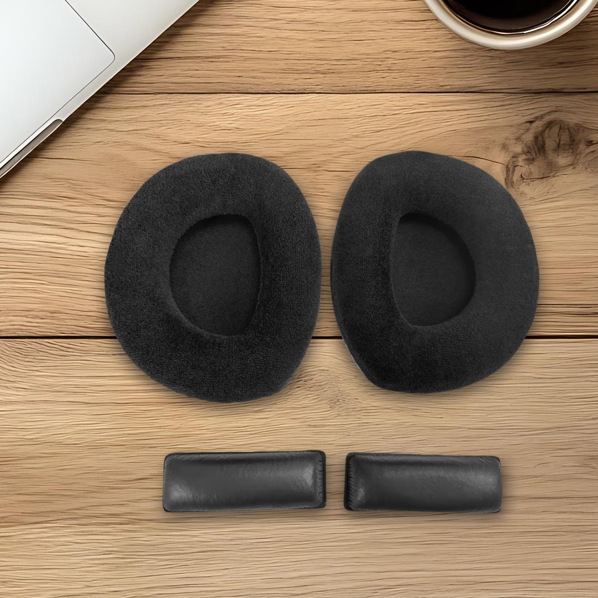 Dwa czarne nauszniki i dwa skórzane paski na drewnianej powierzchni.
