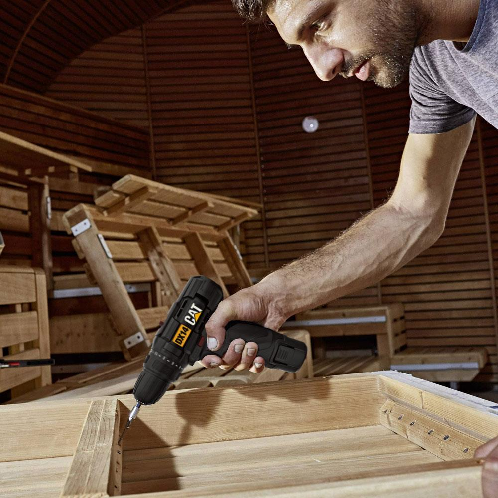 Uomo fora legno in una cabina di legno con trapano CAT.