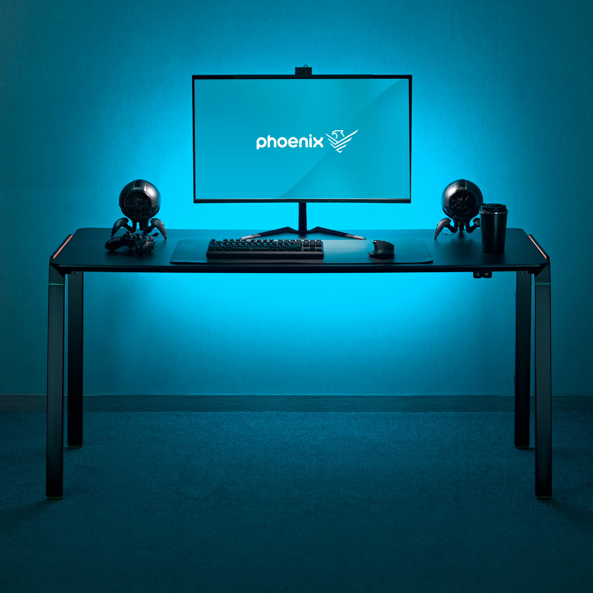 Un escritorio con un monitor, teclado, ratón y dos altavoces, iluminado en azul.