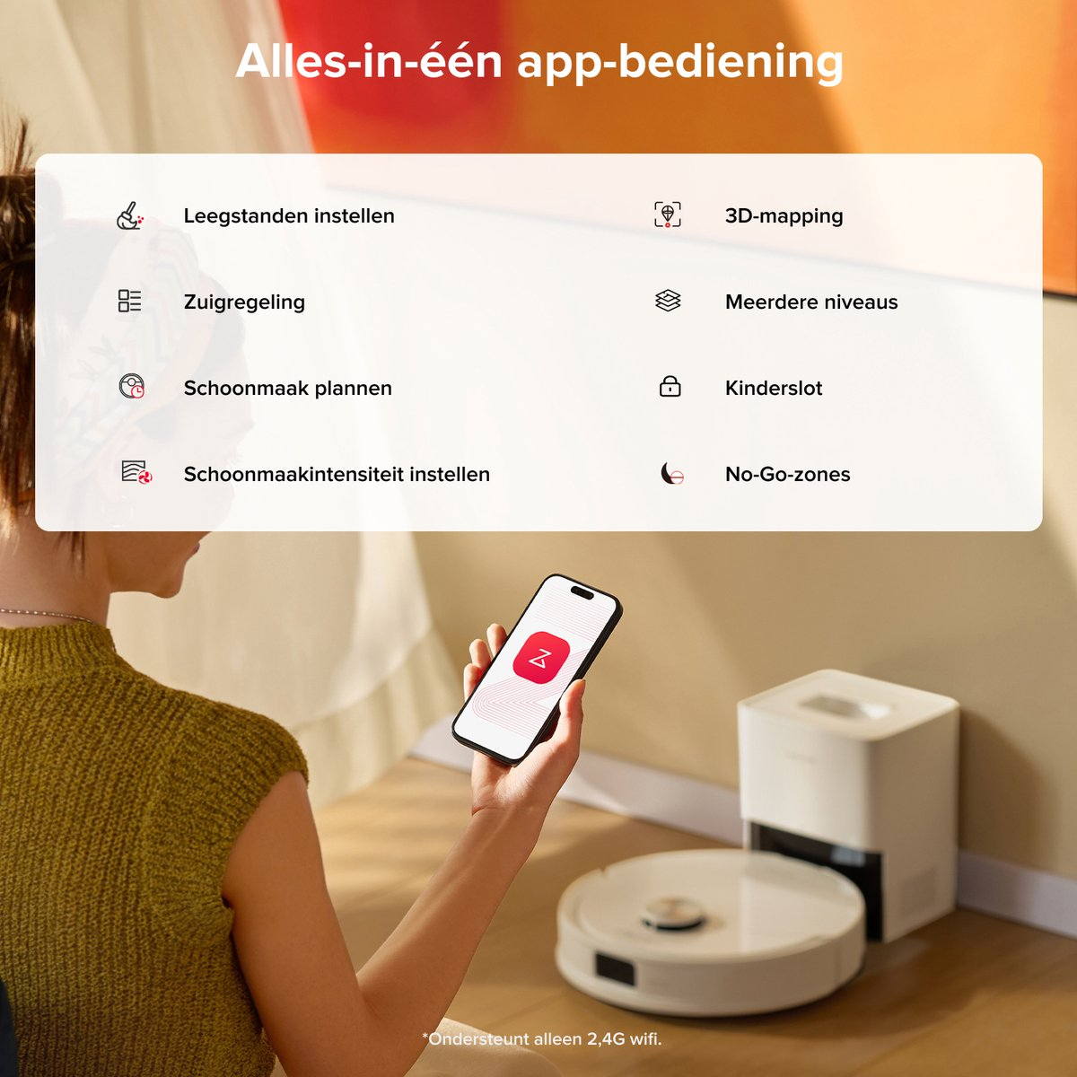 Une personne tient un smartphone avec une application, à côté d'un aspirateur robot.