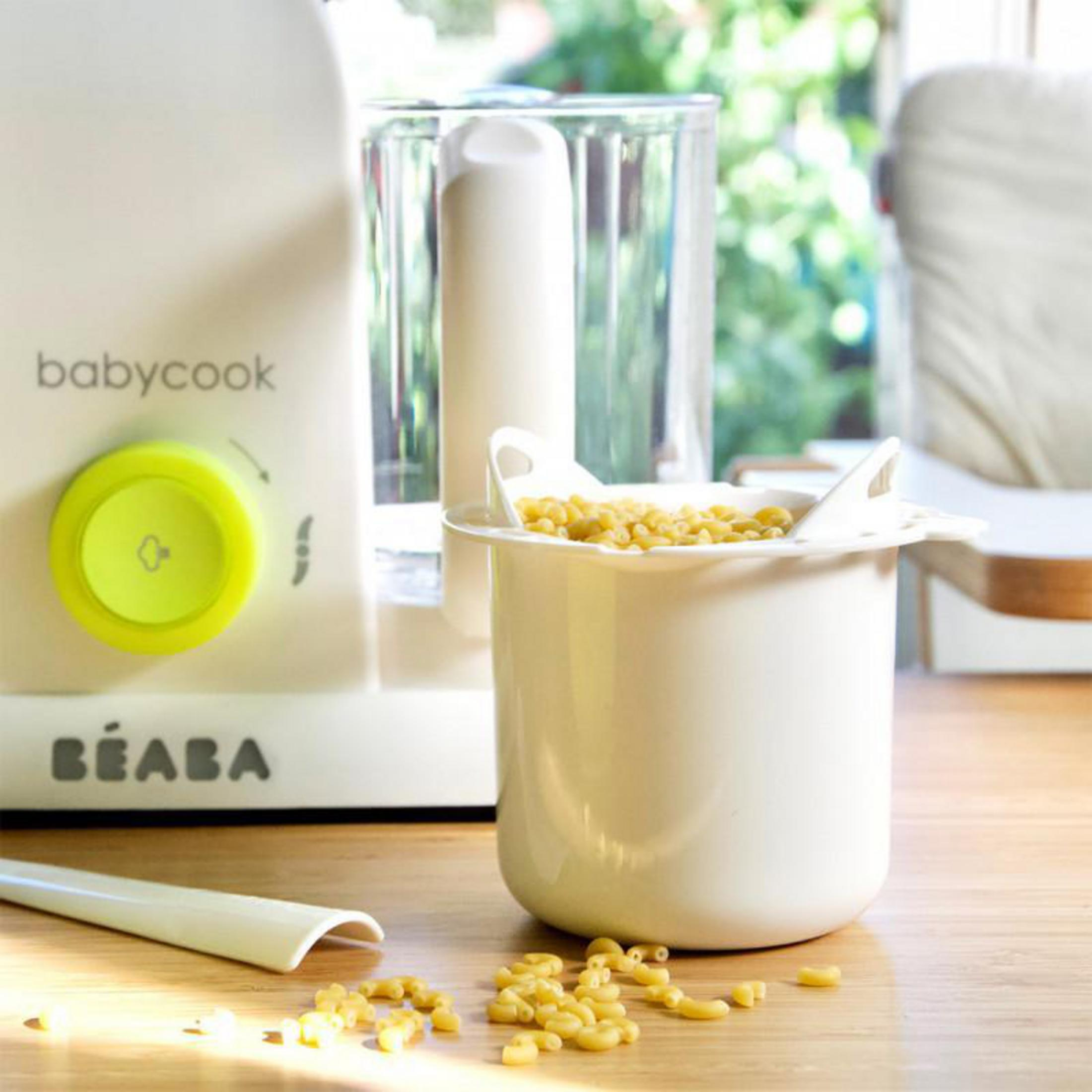 Electrodoméstico Babycook con mando amarillo, al lado un colador lleno de pasta.
