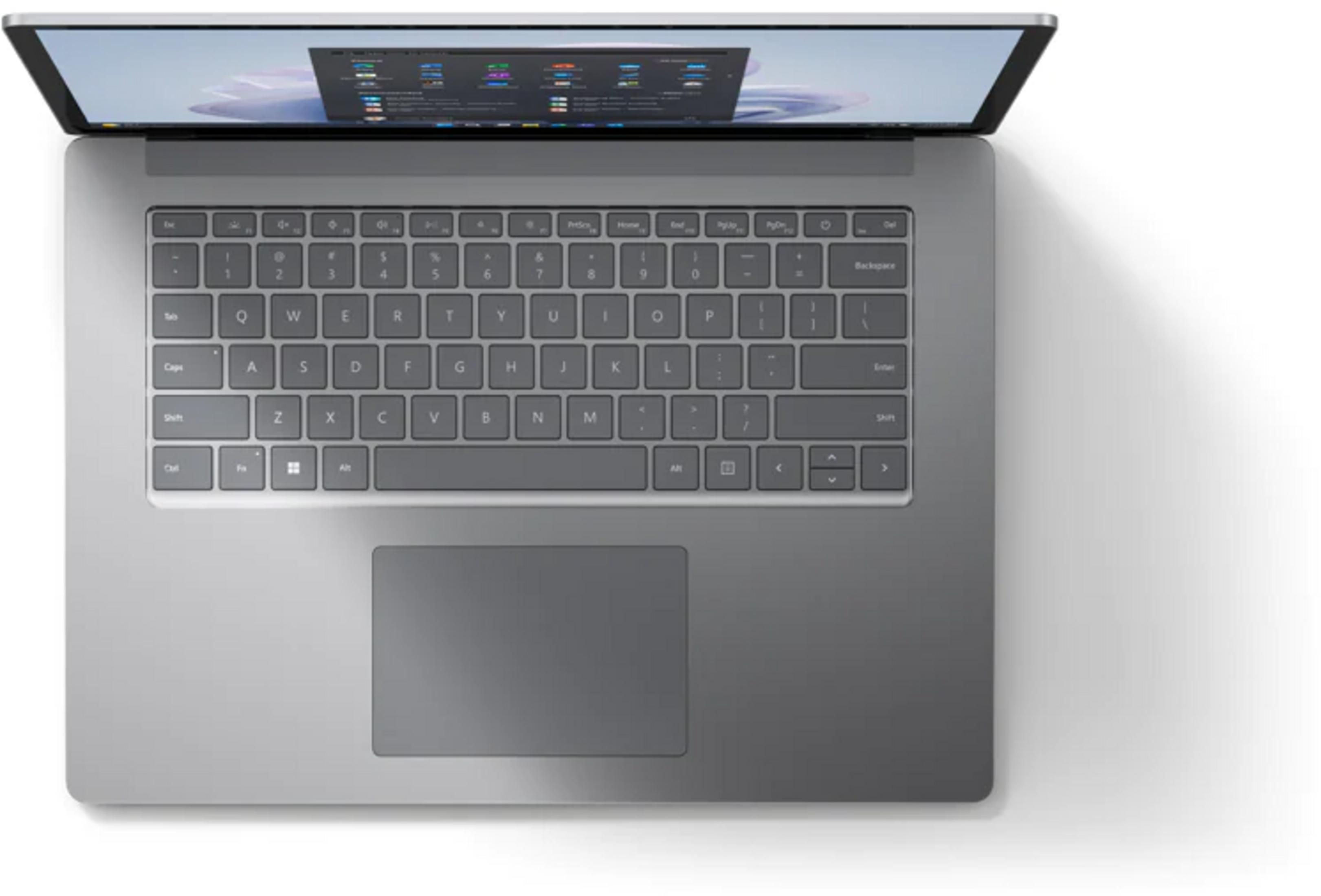 Un portátil plateado con la pantalla abierta, mostrando teclado y touchpad.