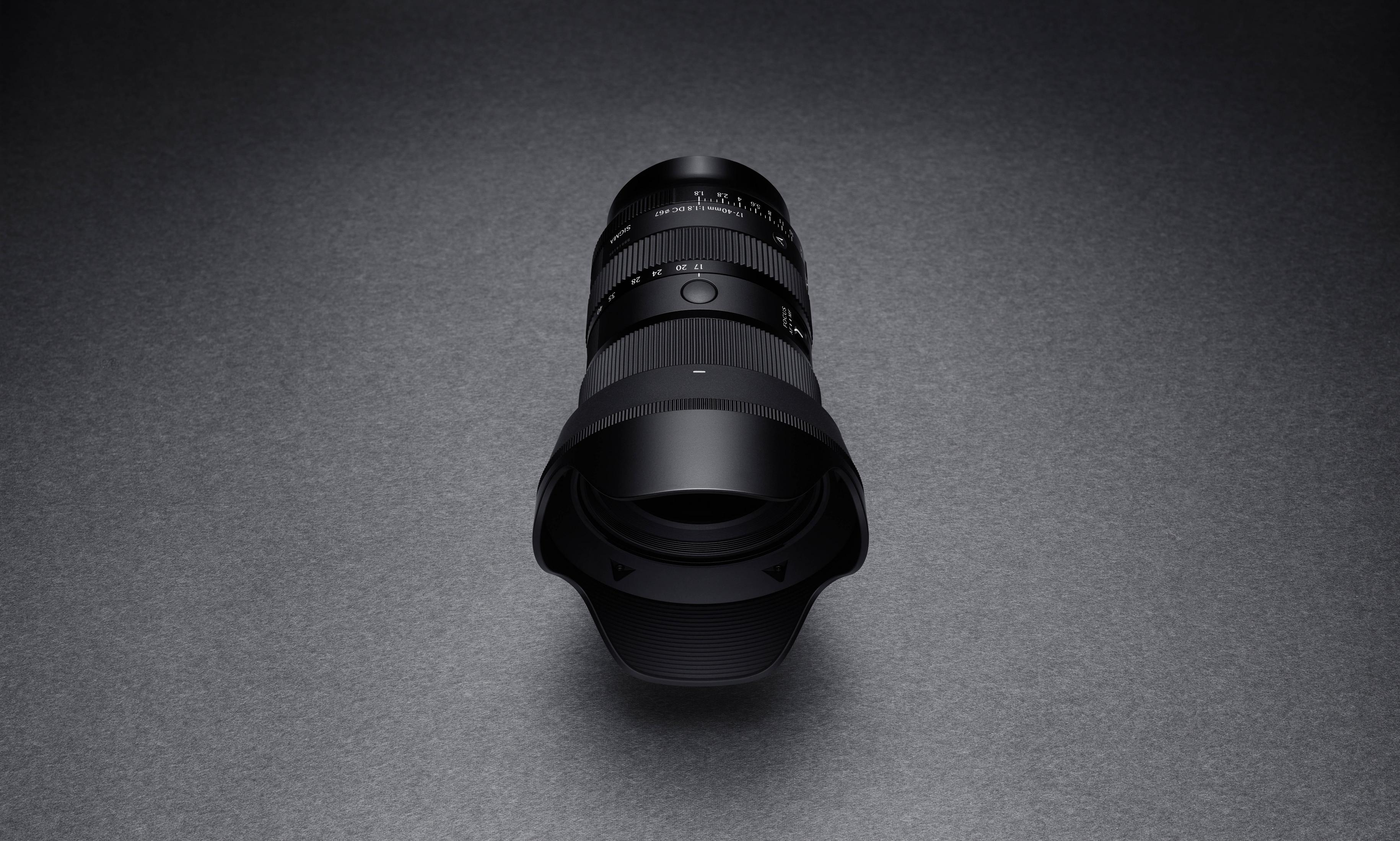 Schwarzes Sigma 17-40mm Objektiv mit Fokus- und Zoomringen auf dunklem Hintergrund.