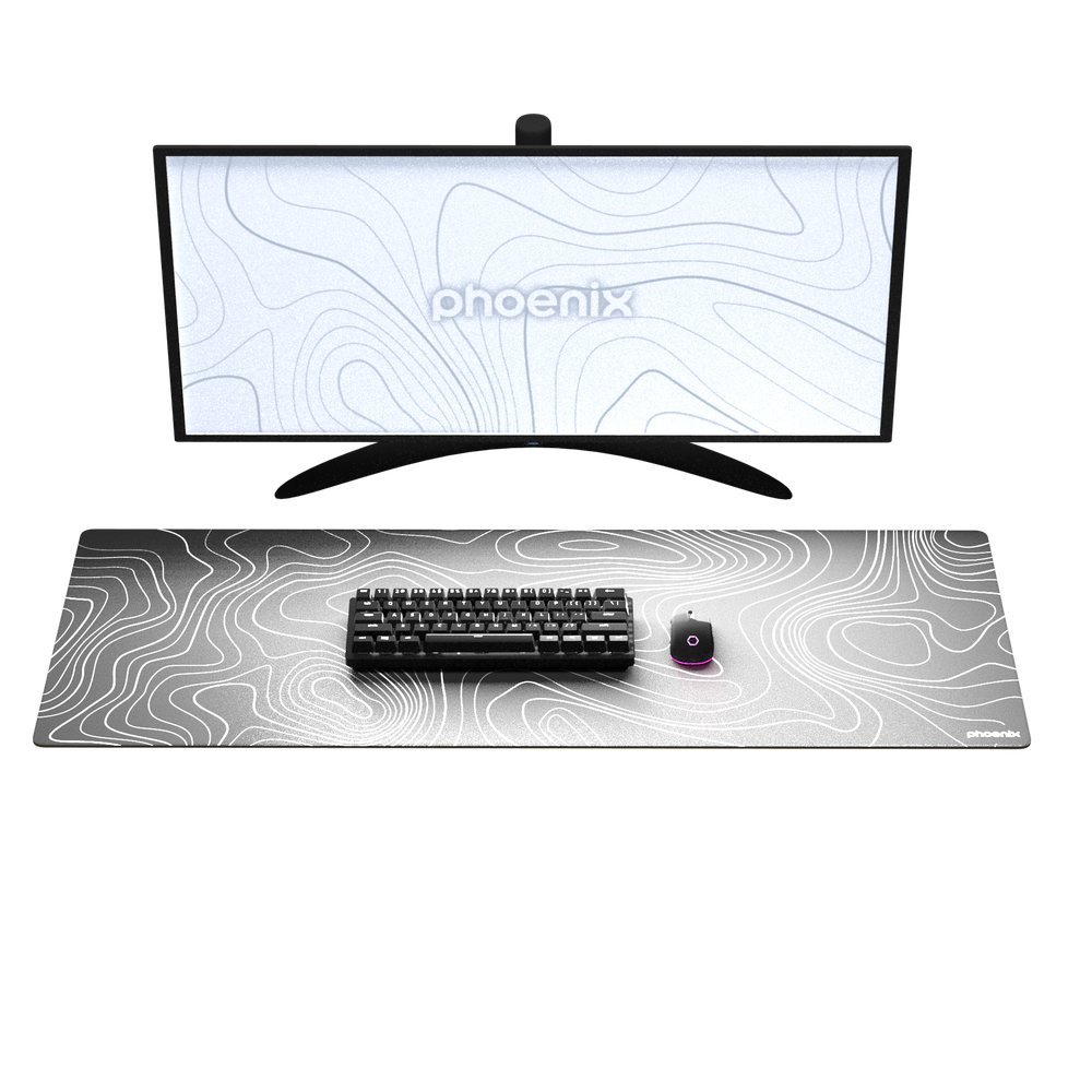 Un monitor y teclado con ratón sobre una alfombrilla con patrón topográfico.