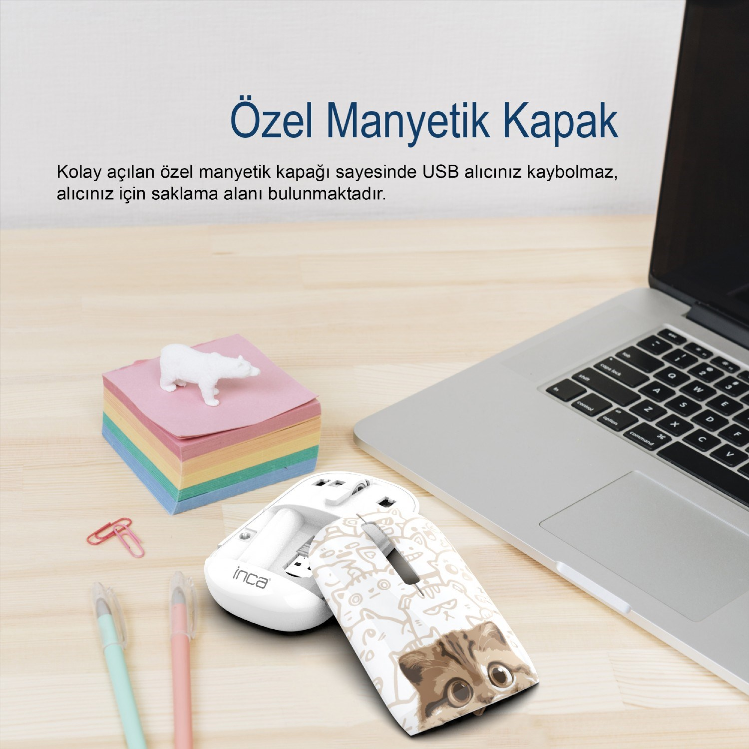 Biała mysz komputerowa z motywem kota obok laptopa i notatników.