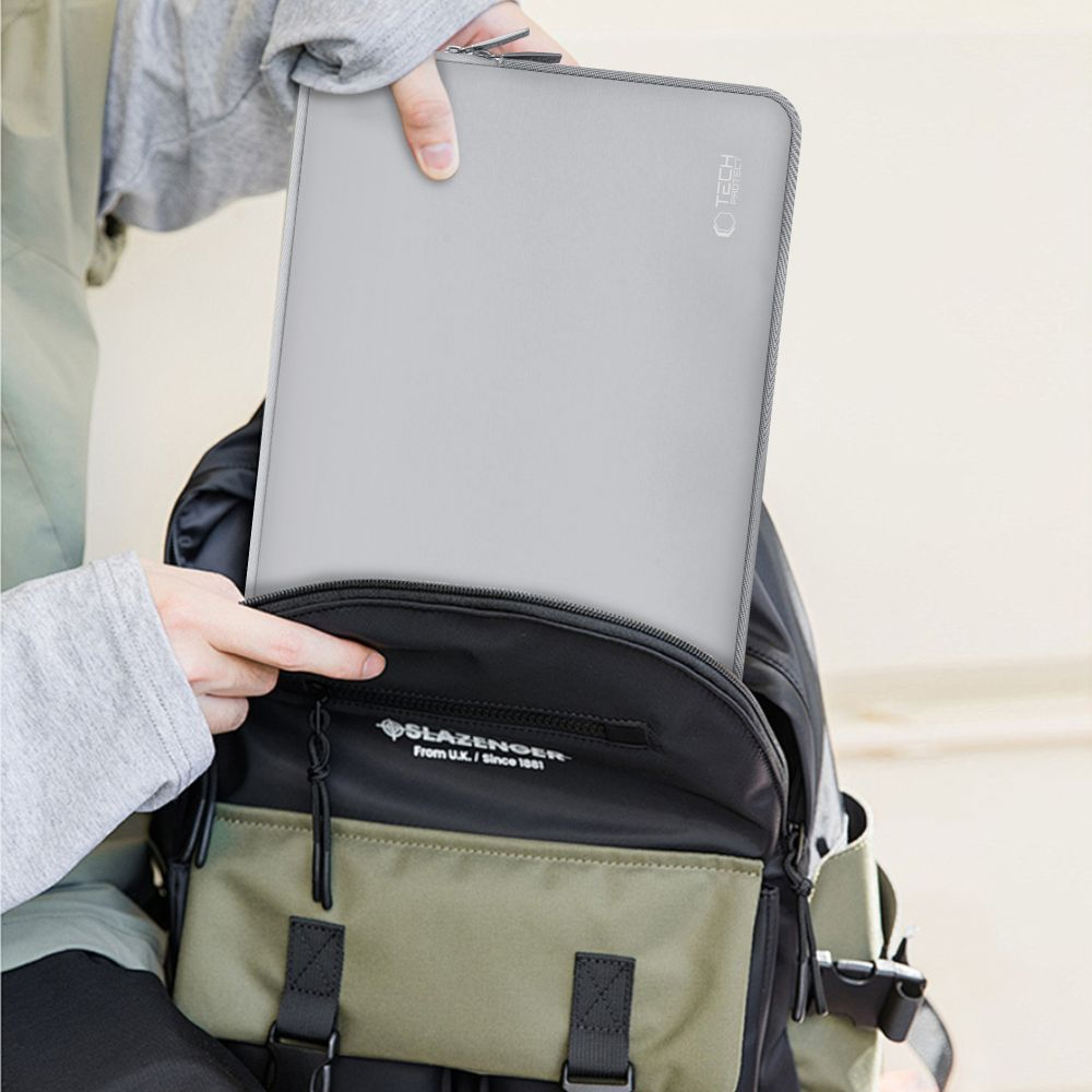 Graue Laptoptasche wird in einen Rucksack gesteckt. Detailaufnahme.