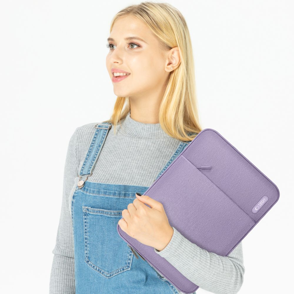 Frau in Latzhose hält eine lila Laptoptasche mit Reißverschlusstasche.