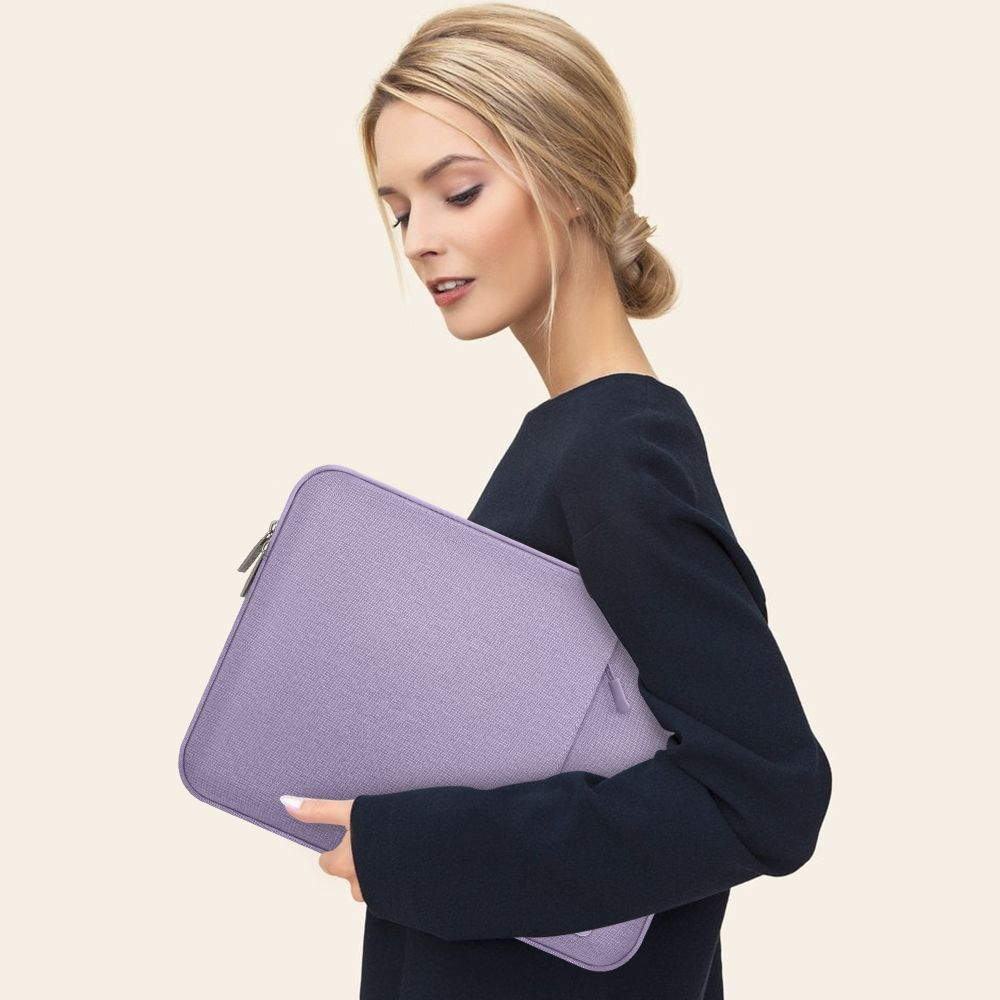 Eine Frau mit blondem Haar hält eine lila Laptoptasche vor sich.