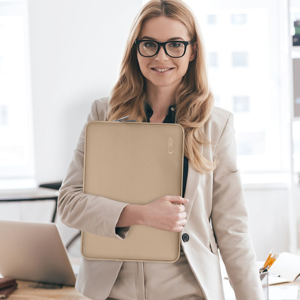 Eine Frau mit Brille hält eine goldene Laptoptasche.