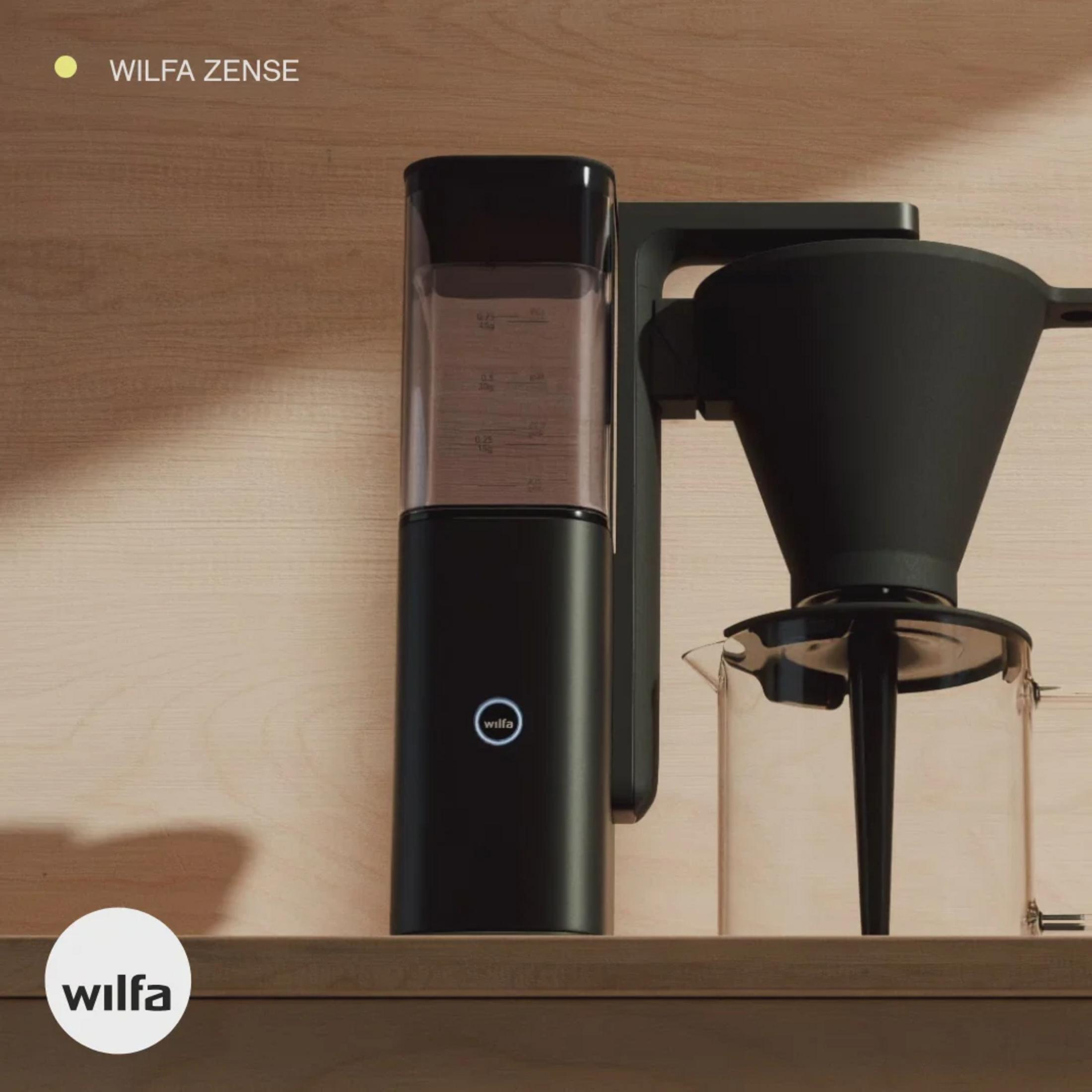 Schwarze Kaffeemaschine mit Wassertank und Glaskaraffe auf Holzregal.
