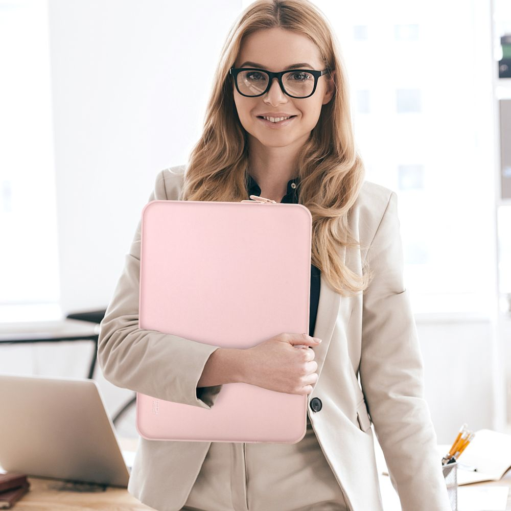 Eine Frau mit Brille hält eine rosafarbene Laptoptasche in einem Büro.