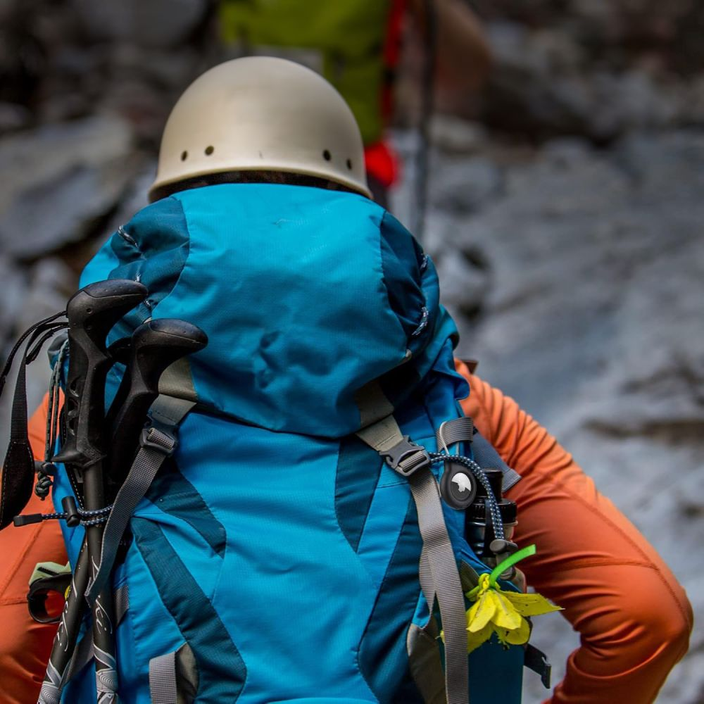 Ein Wanderer mit blauem Rucksack und beigefarbener Helm trägt orangefarbene Kleidung.