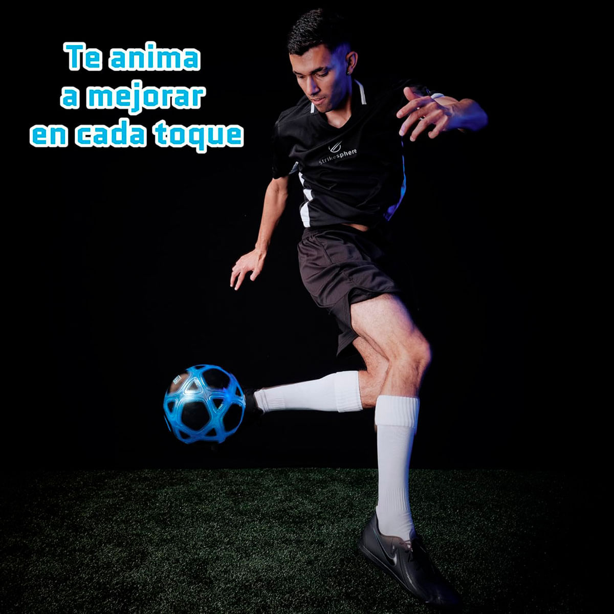 Un calciatore in bianco e nero calcia un pallone blu su erba sintetica.