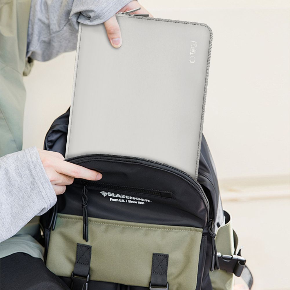 Eine Person packt eine graue Laptoptasche in einen Rucksack.