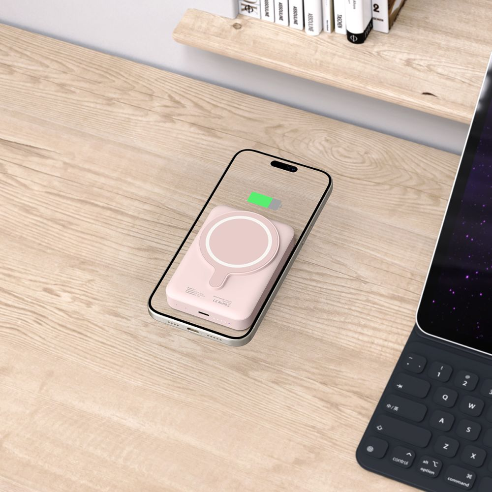 Ein rosa MagSafe Ladegerät auf einem Handy auf einem Holztisch.
