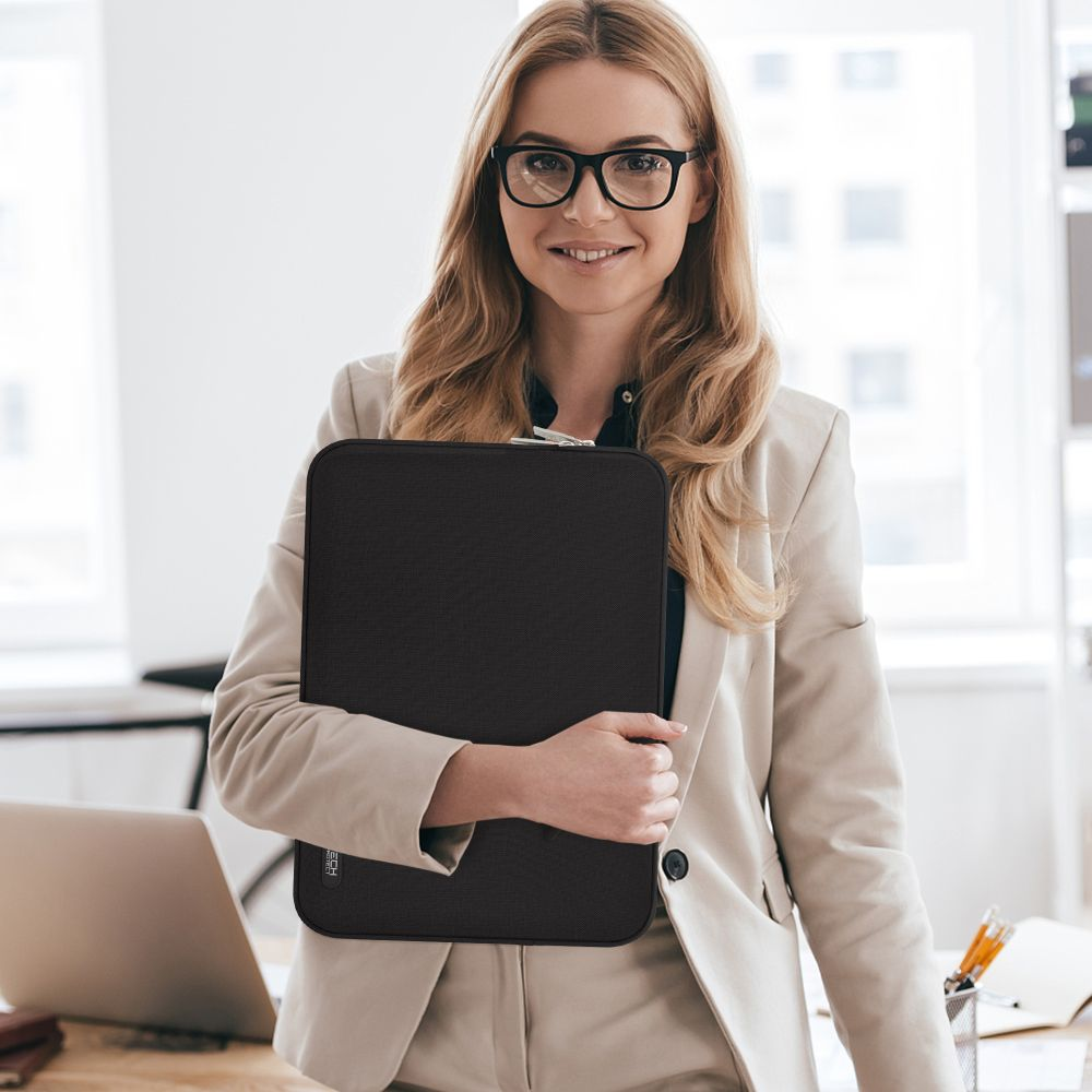 Eine Frau im Anzug hält eine schwarze Laptoptasche.