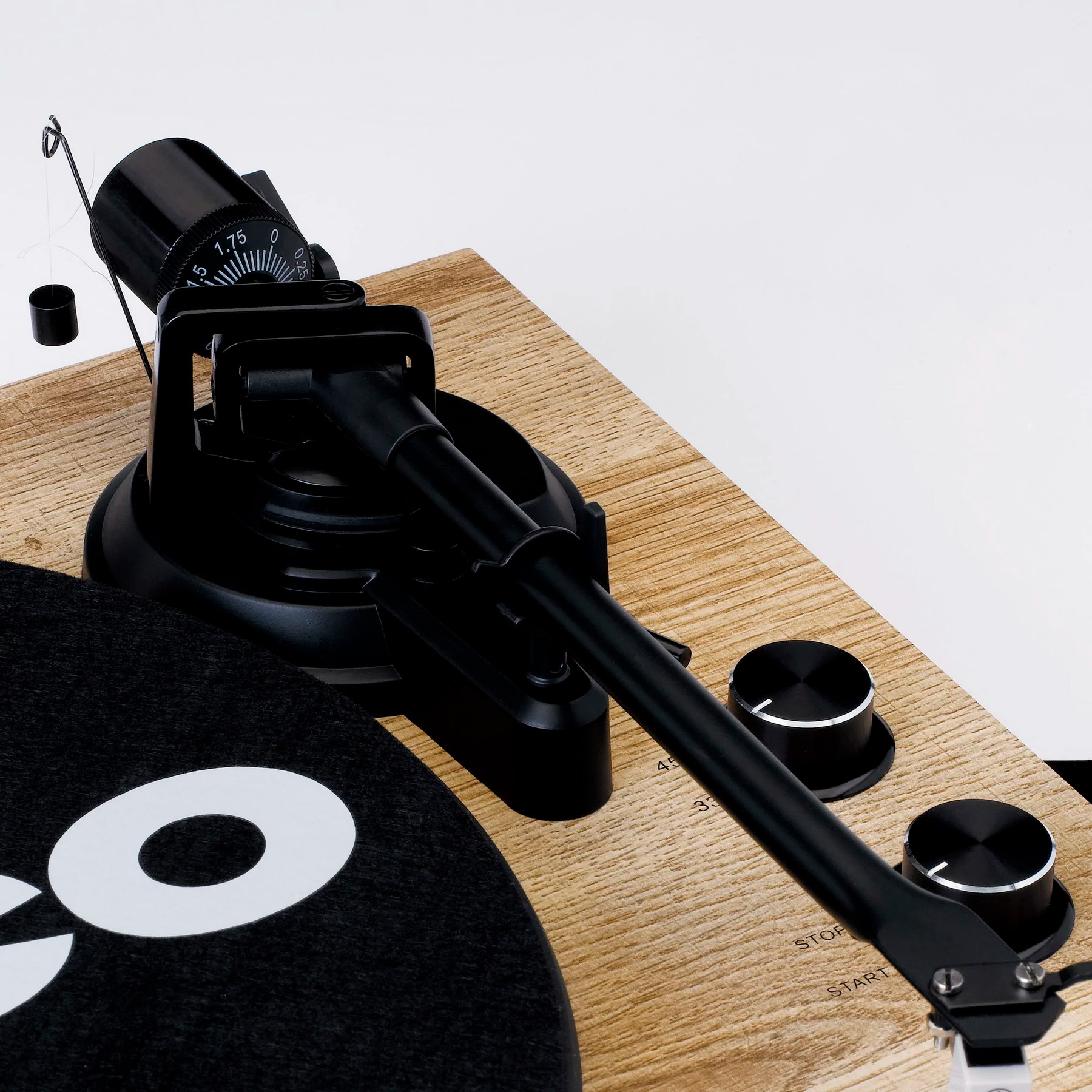 Zbliżenie czarnego ramienia gramofonu na płycie z drewnianym usłojeniem.