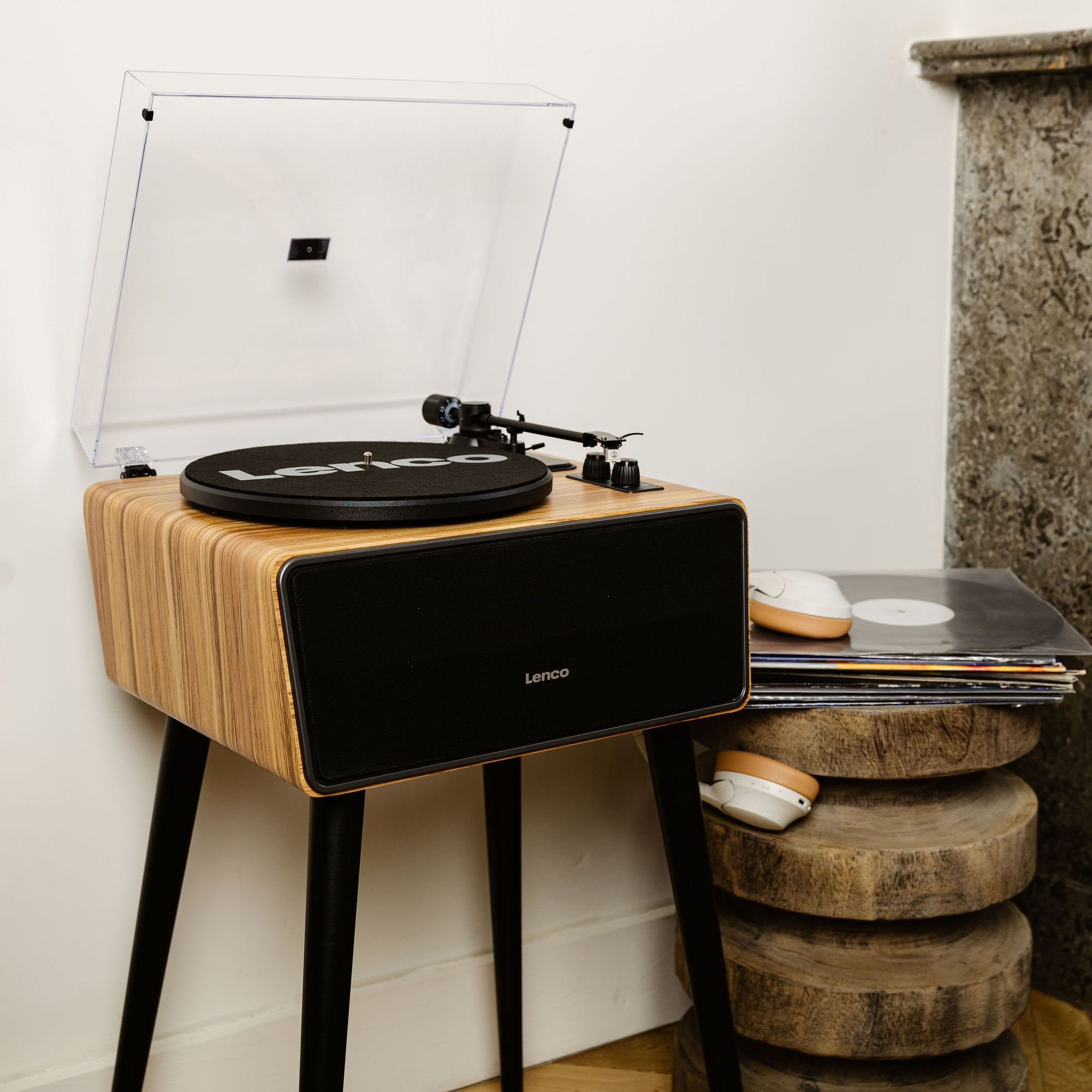 Ein Plattenspieler mit Holzakzenten steht neben Schallplatten und Kopfhörern.