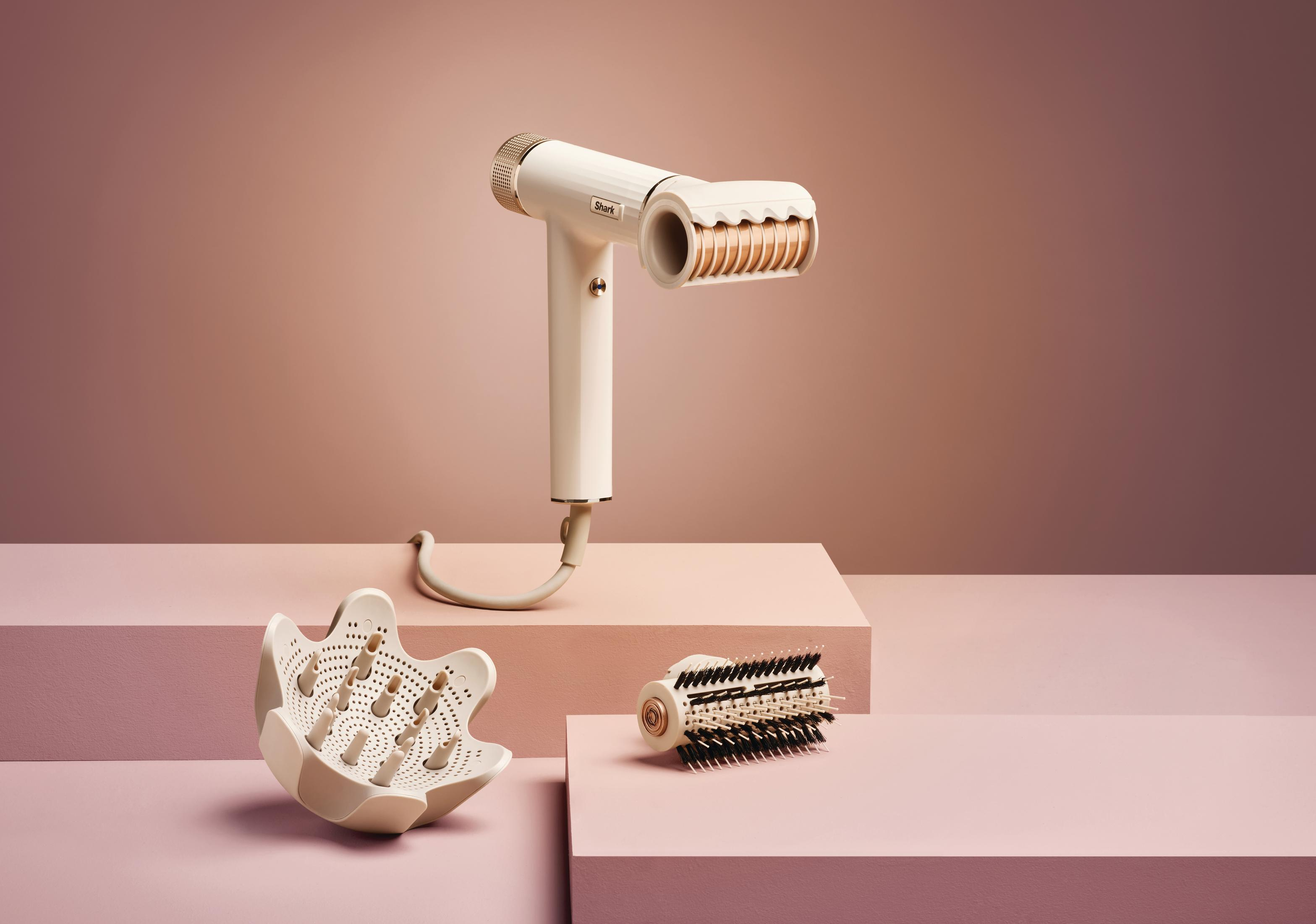 Biała suszarka do włosów ze złotymi akcentami, dyfuzorem i szczotką.