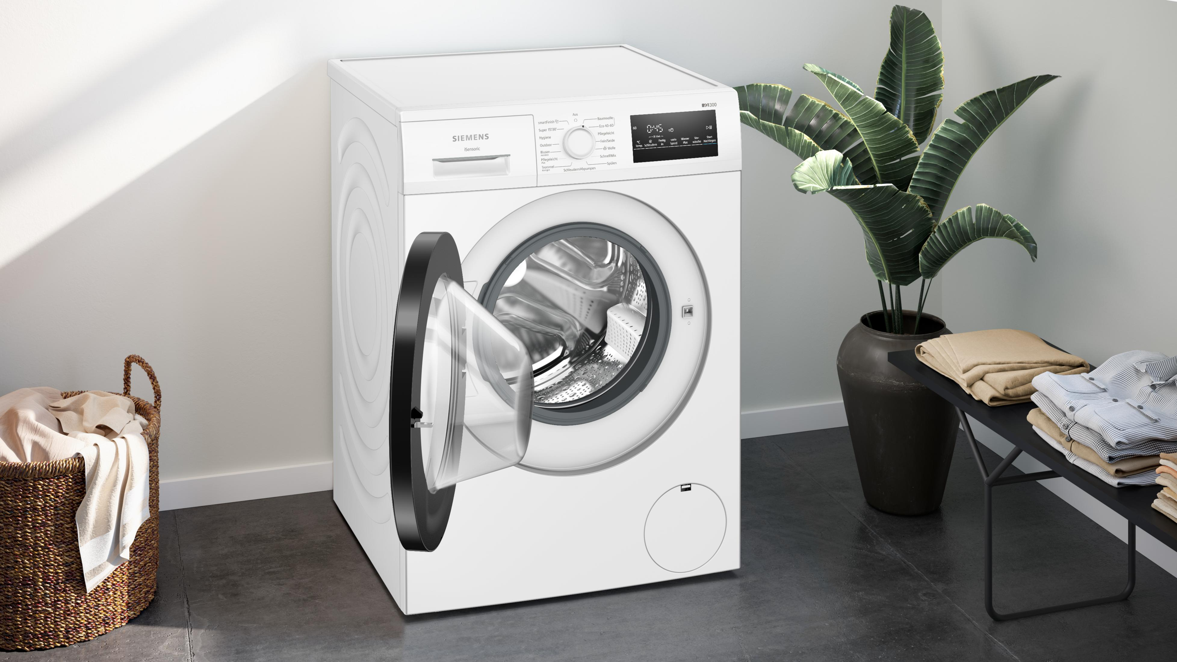 Weiße Siemens Waschmaschine mit offener Tür, Wäschekorb und Pflanzen.