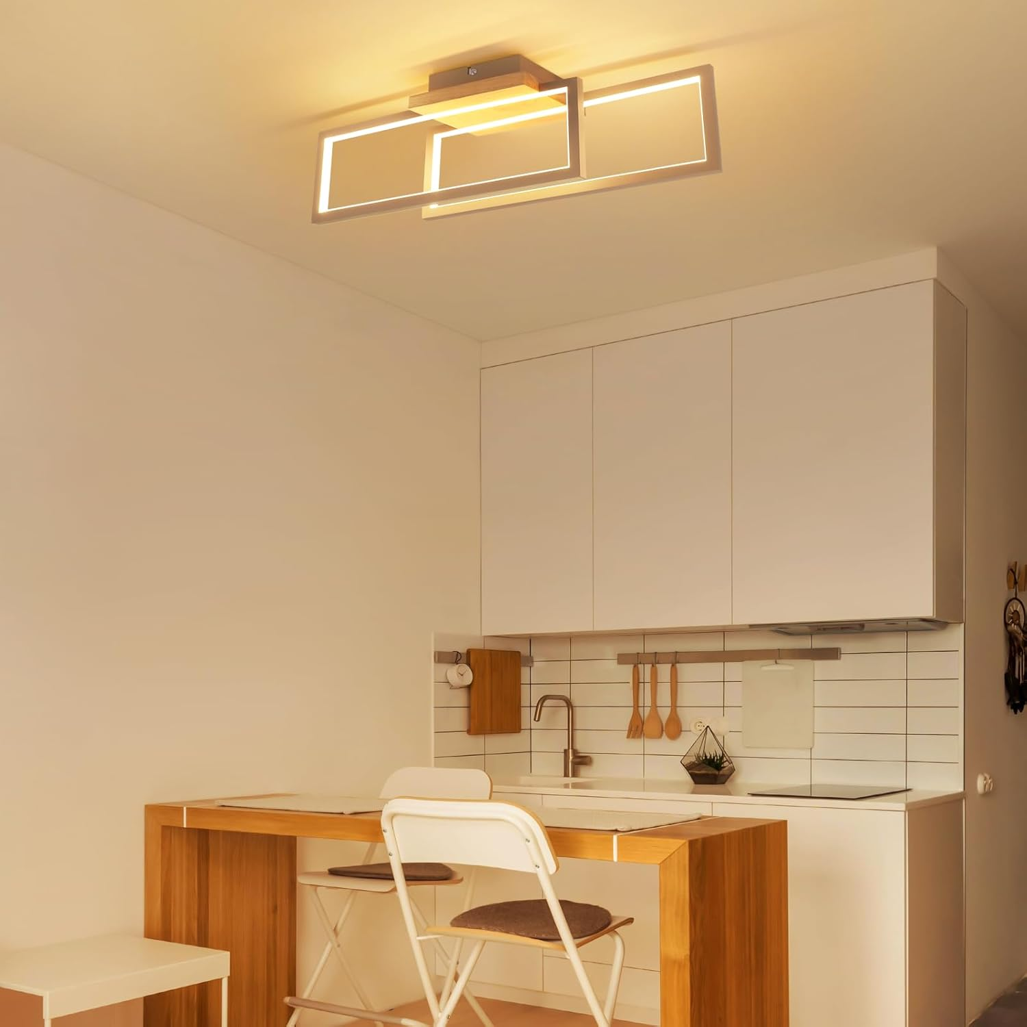 Cucina moderna con tavolo in legno, sedie e mobili bianchi.