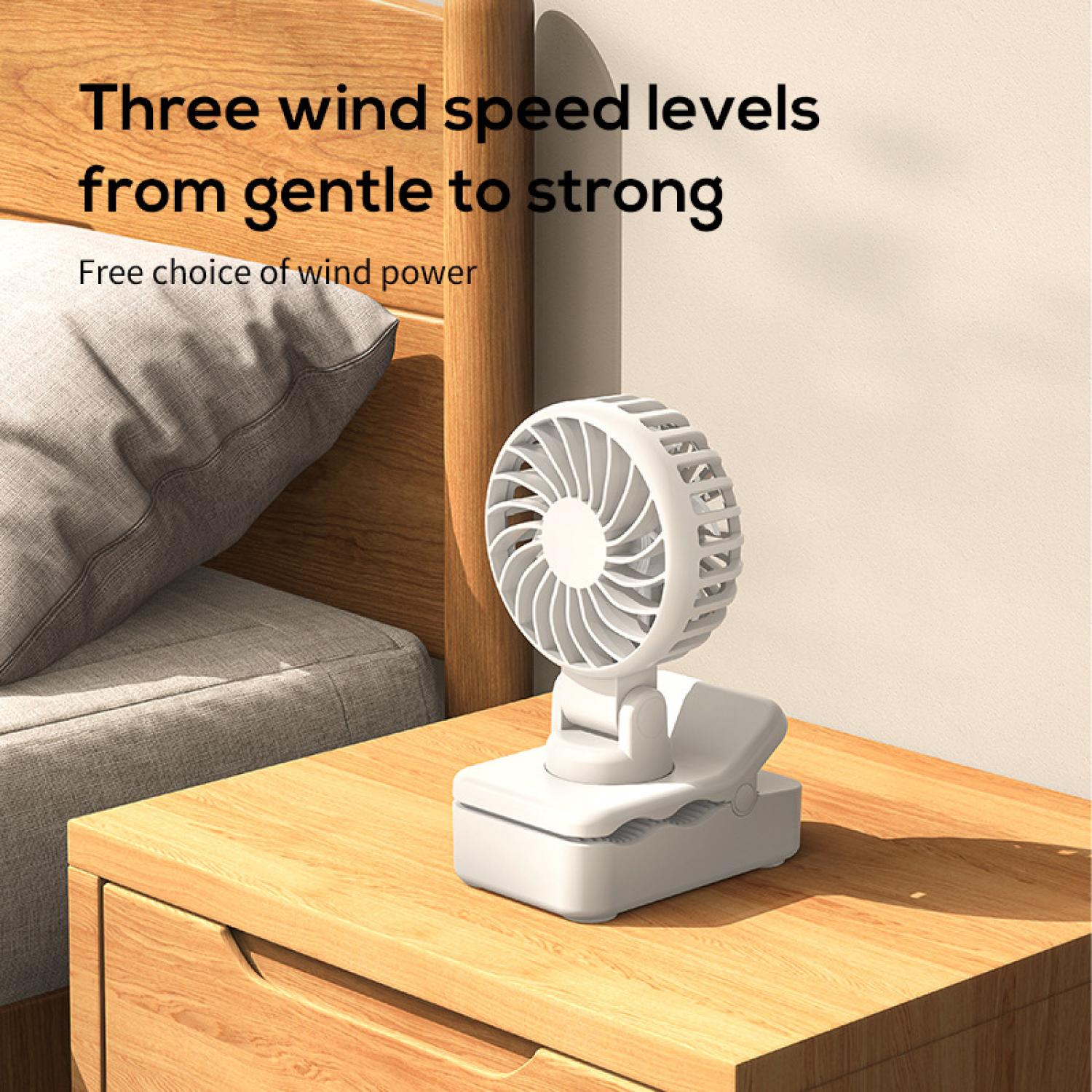 Ein kleiner weißer Ventilator mit Klemme auf einem Nachttisch.