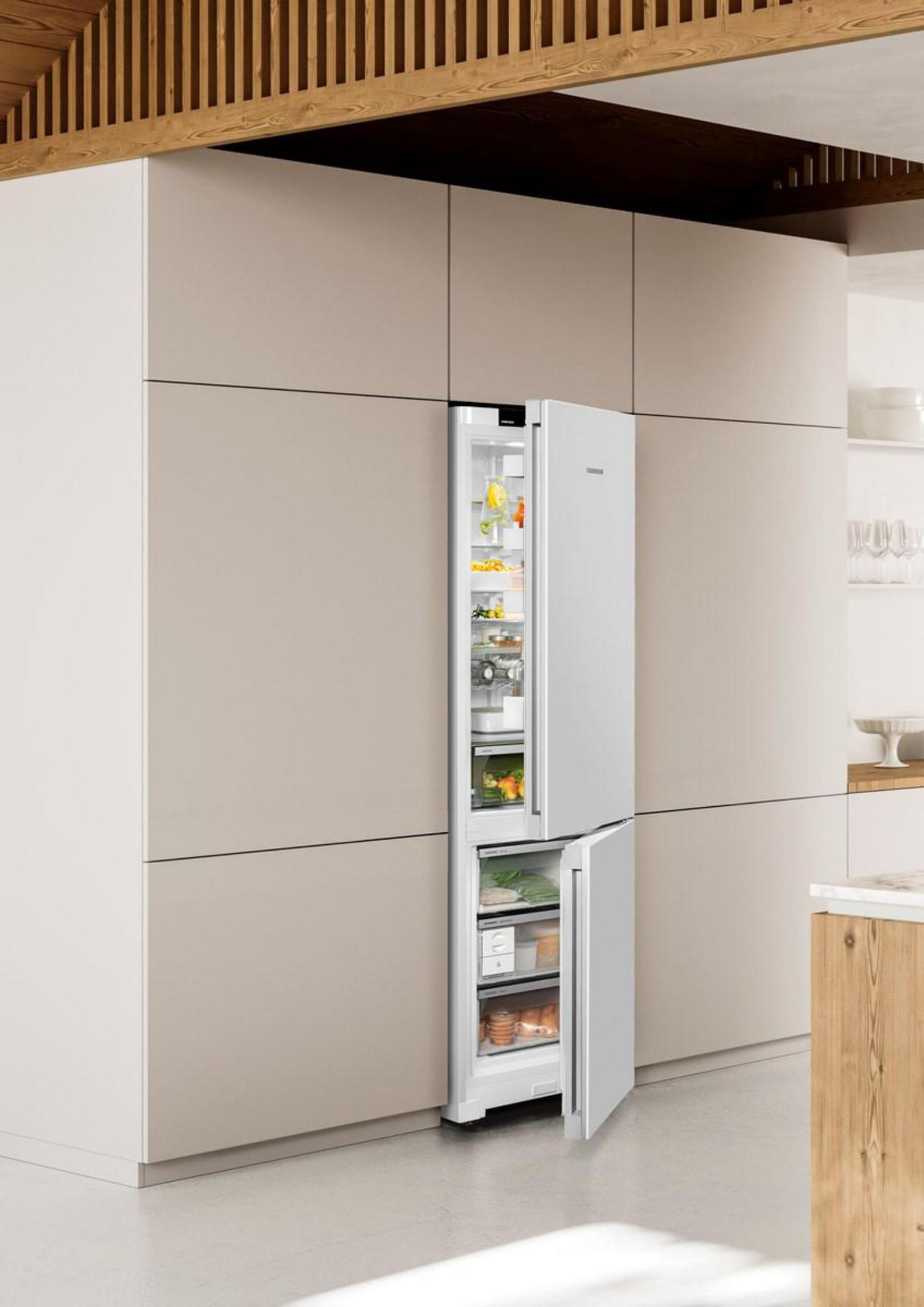 Un refrigerador blanco con la puerta abierta está en una cocina moderna con detalles de madera.