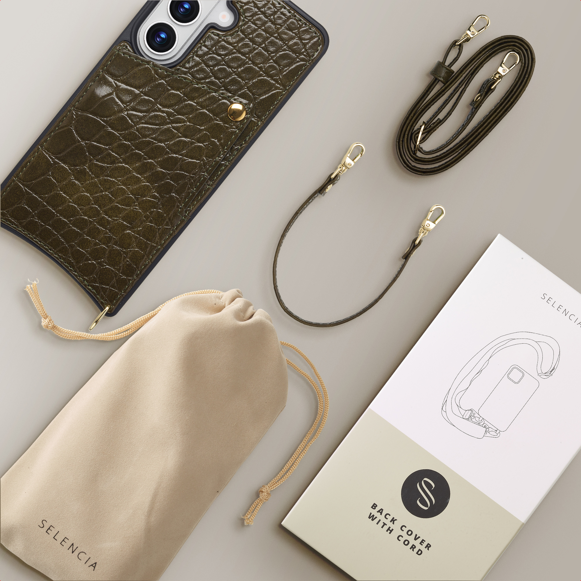 Donkergroene krokodillenleren telefoonhoes met riem, zakje en verpakking.
