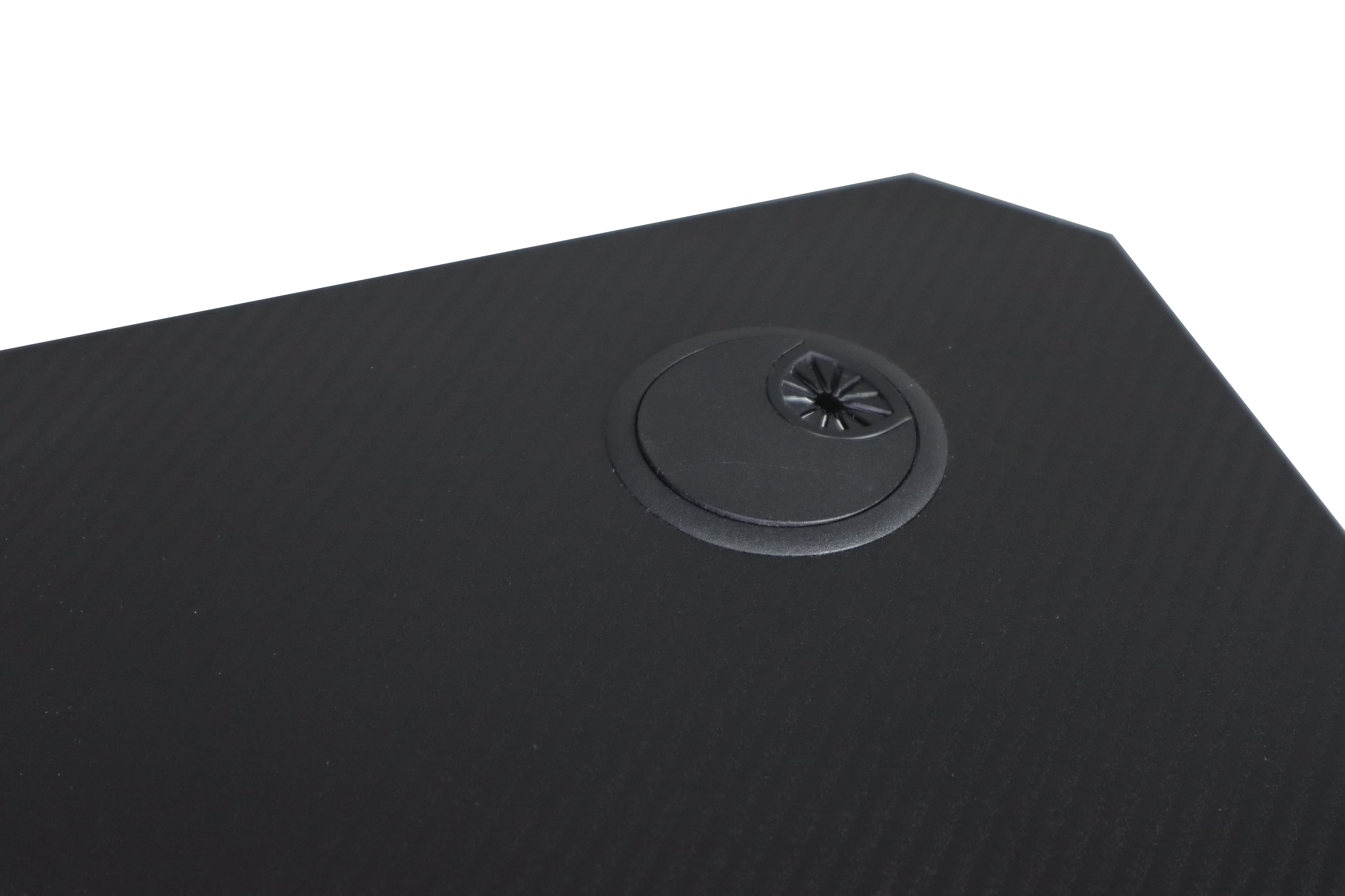 Czarna powierzchnia biurka z przelotką na kabel i prążkowaną fakturą.