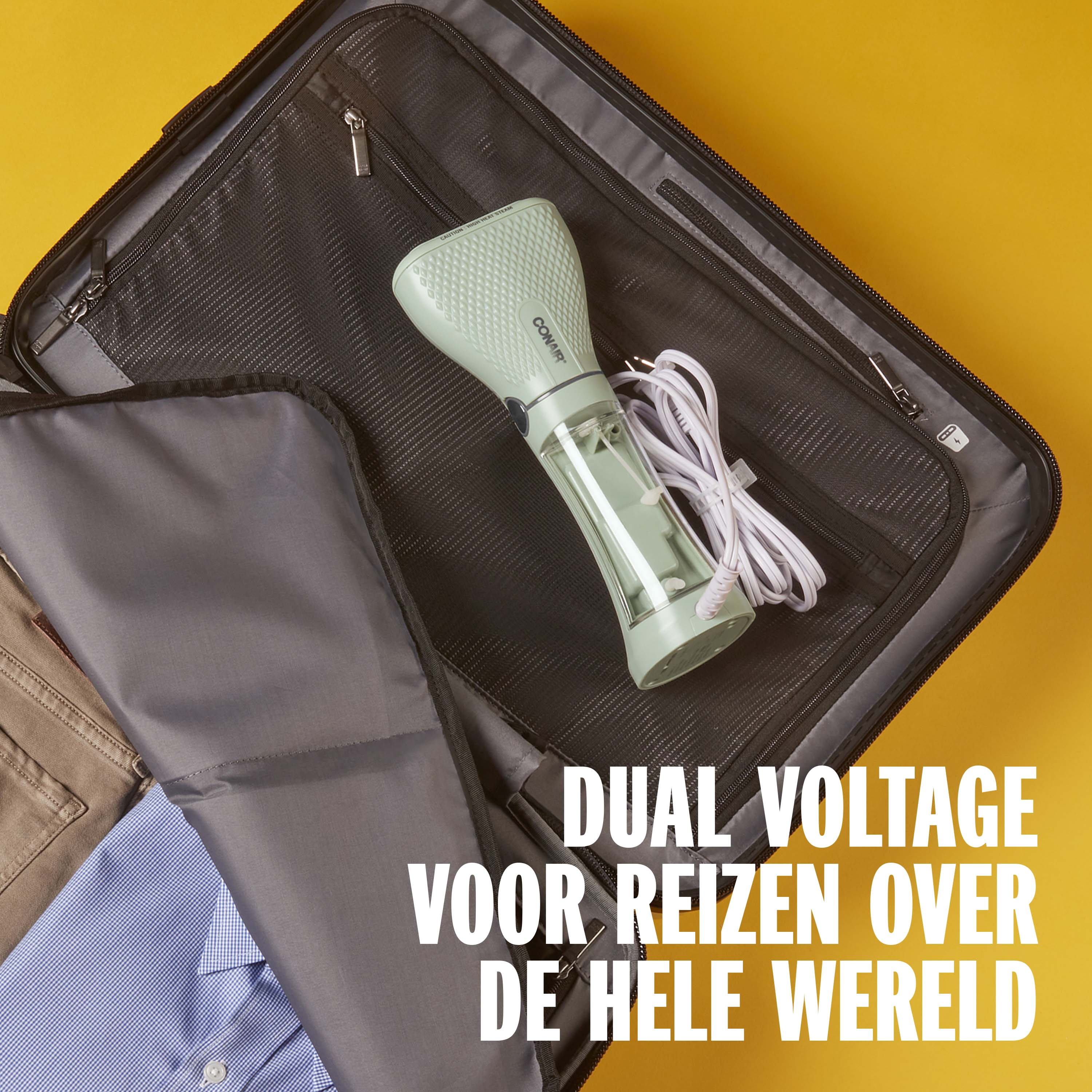 A green hand steamer lies in a suitcase next to clothes.