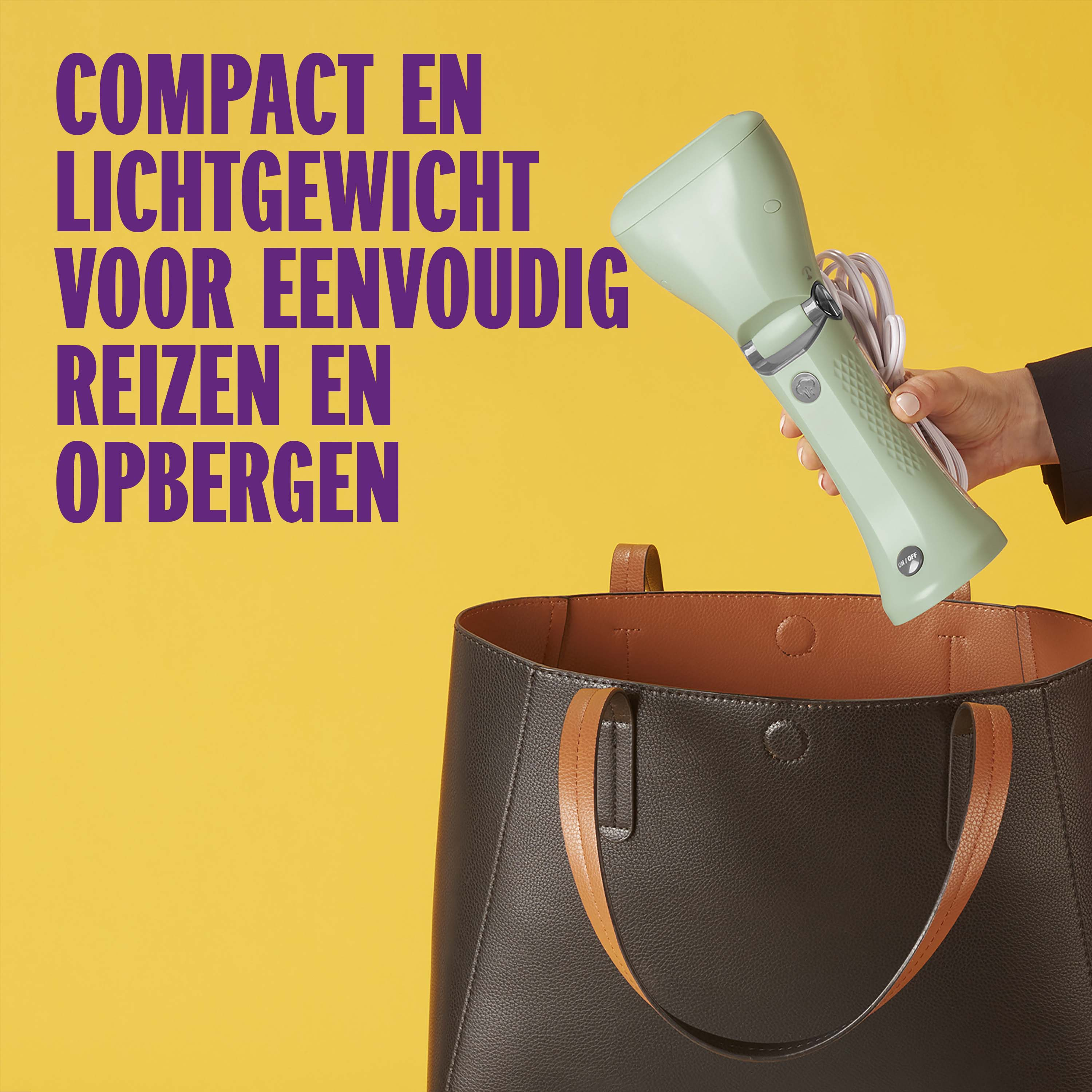 A hand holds a green steamer over a brown tote bag.