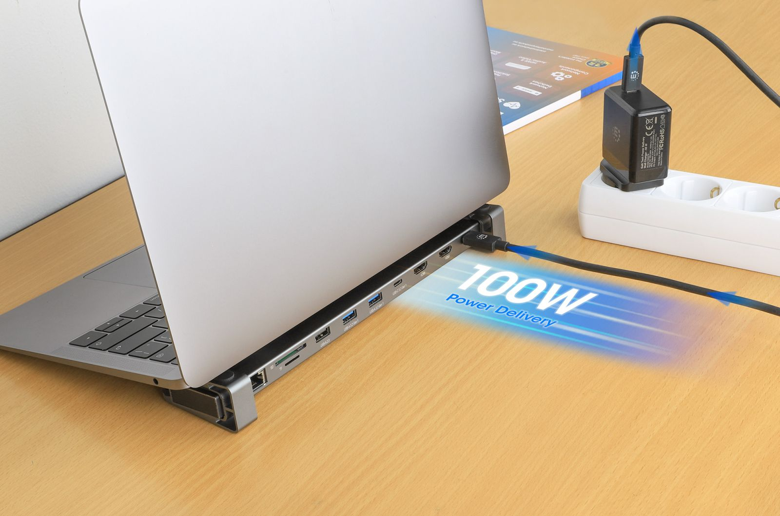 Ein Laptop ist mit einem USB-C-Hub verbunden, der an eine Steckdosenleiste angeschlossen ist.