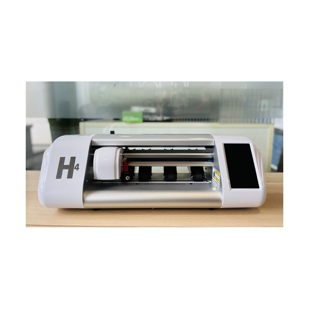 Ein weißer Schneideplotter mit der Aufschrift H4 auf einem Holztisch.