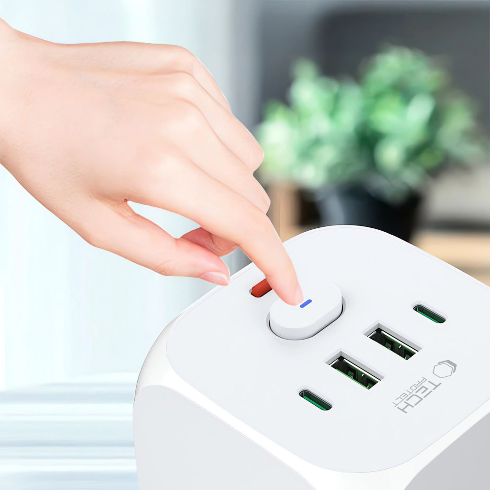 Hand drückt Knopf auf weißem Ladegerät mit USB-Anschlüssen.