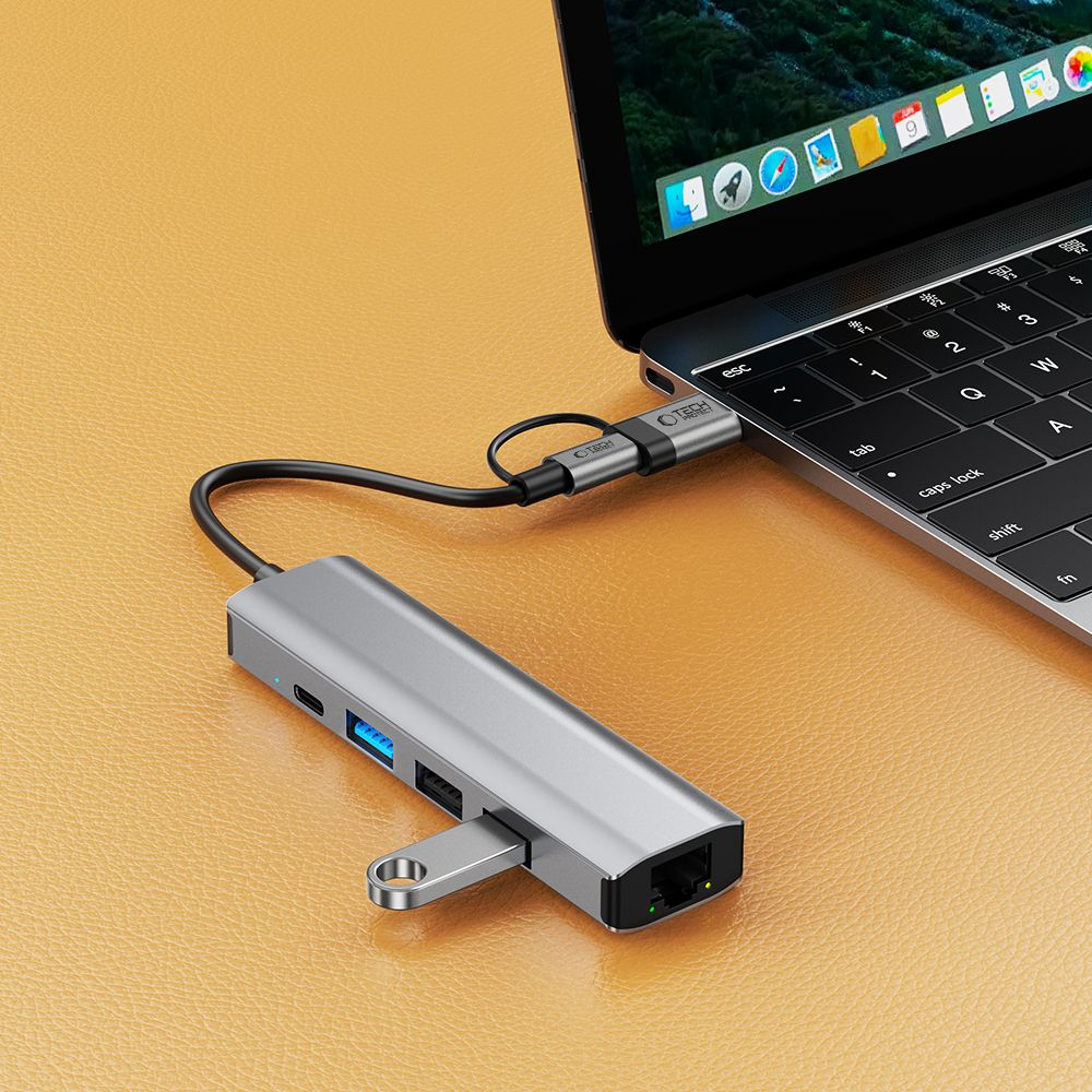 Un hub USB-C argento collegato a un laptop, che mostra le sue porte.