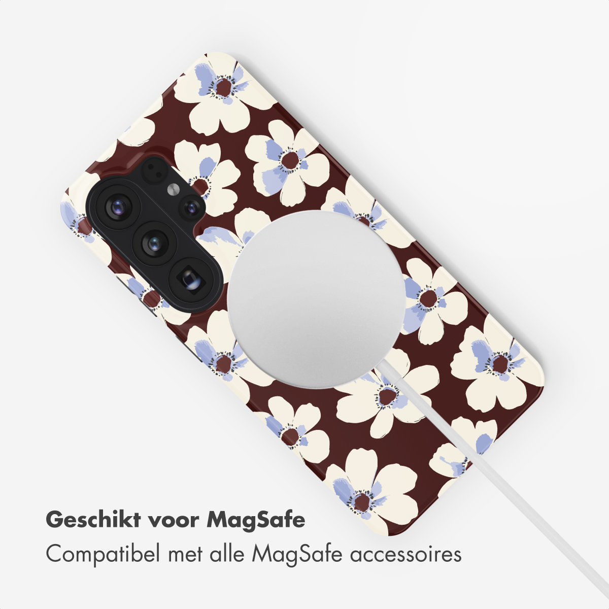 Telefoonhoesje met witte en blauwe bloemen op bruine achtergrond, toont MagSafe-lader.