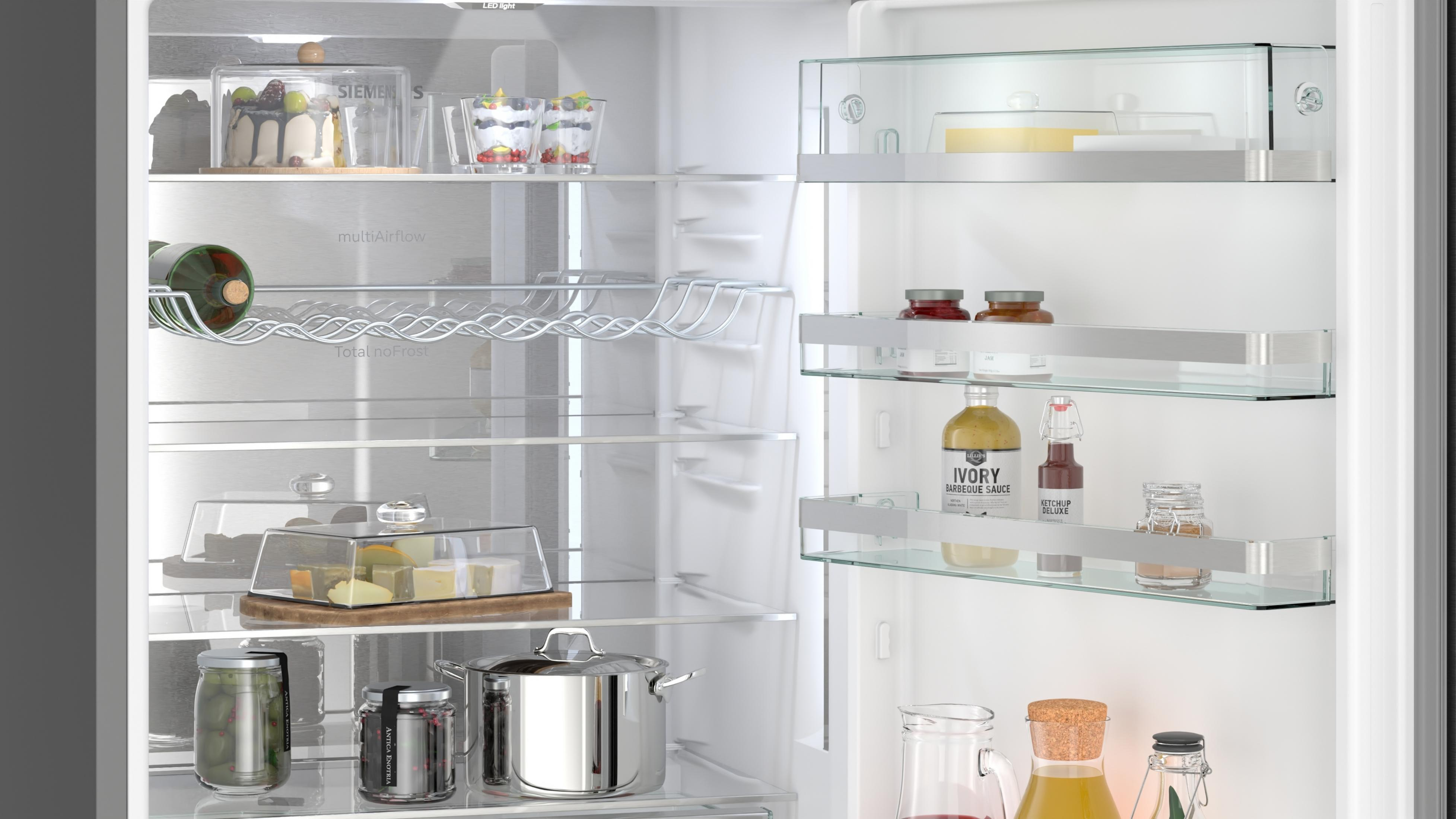 Kühlschrank gefüllt mit Lebensmitteln wie Kuchen, Flaschen, Gläsern, Käse und Töpfen.