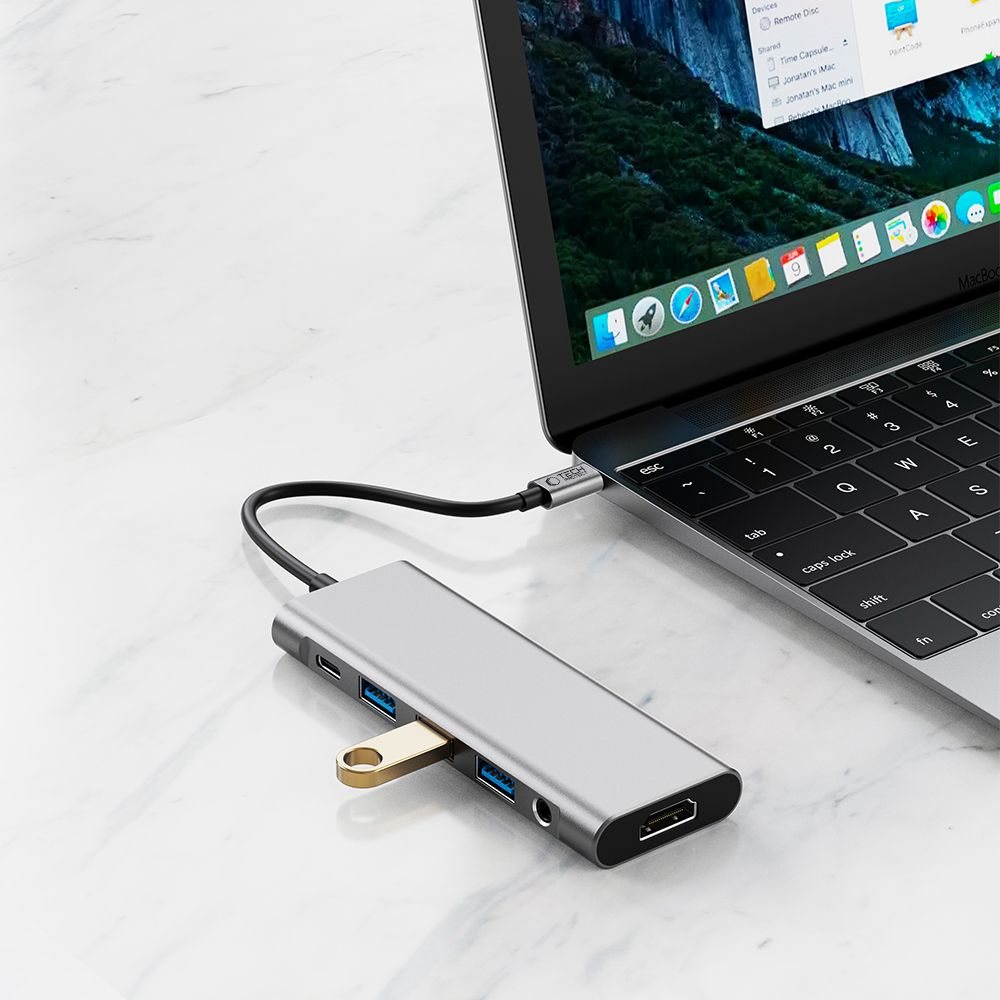 Un hub USB-C argentato collegato a un MacBook. Ha più porte.