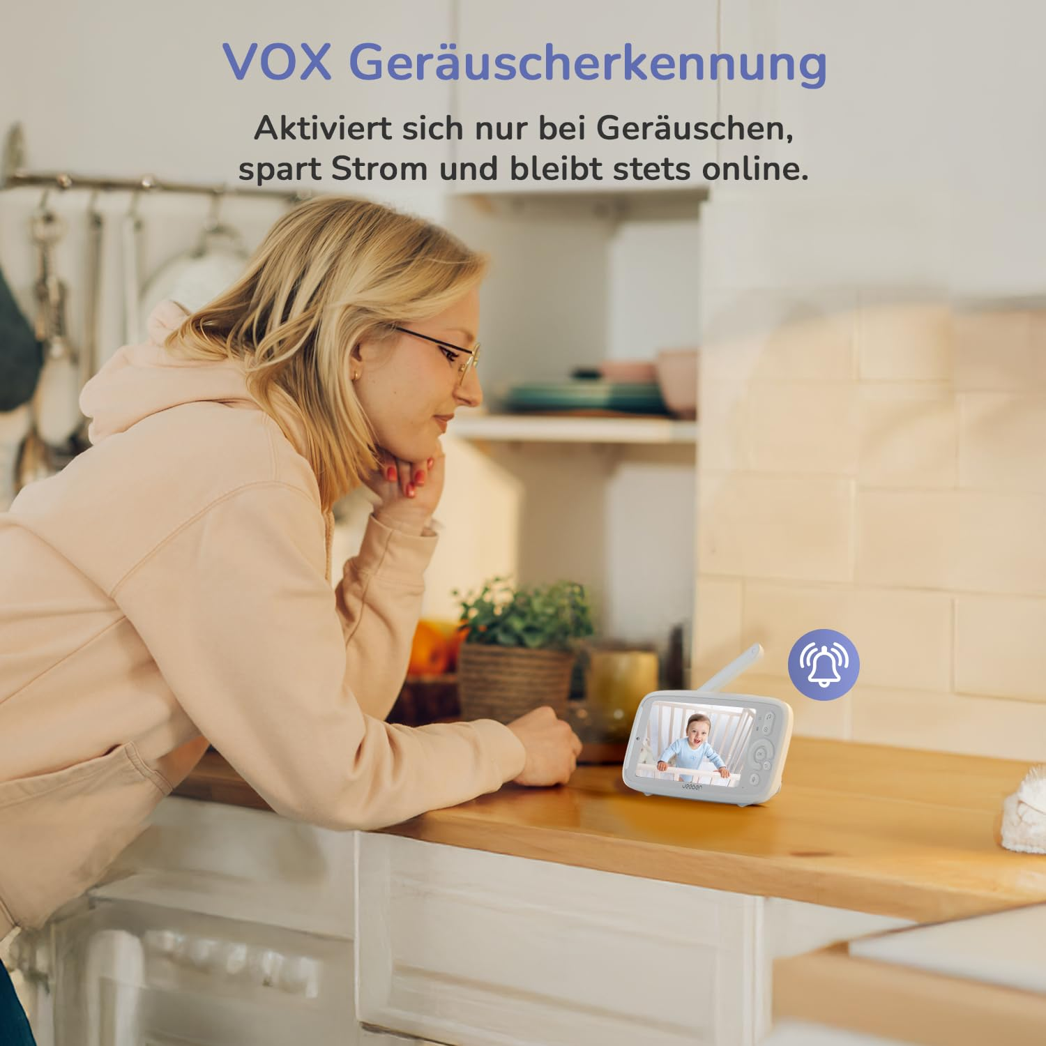 Eine Frau schaut auf einen Babyfon-Bildschirm mit einem Baby und einem Glockensymbol.